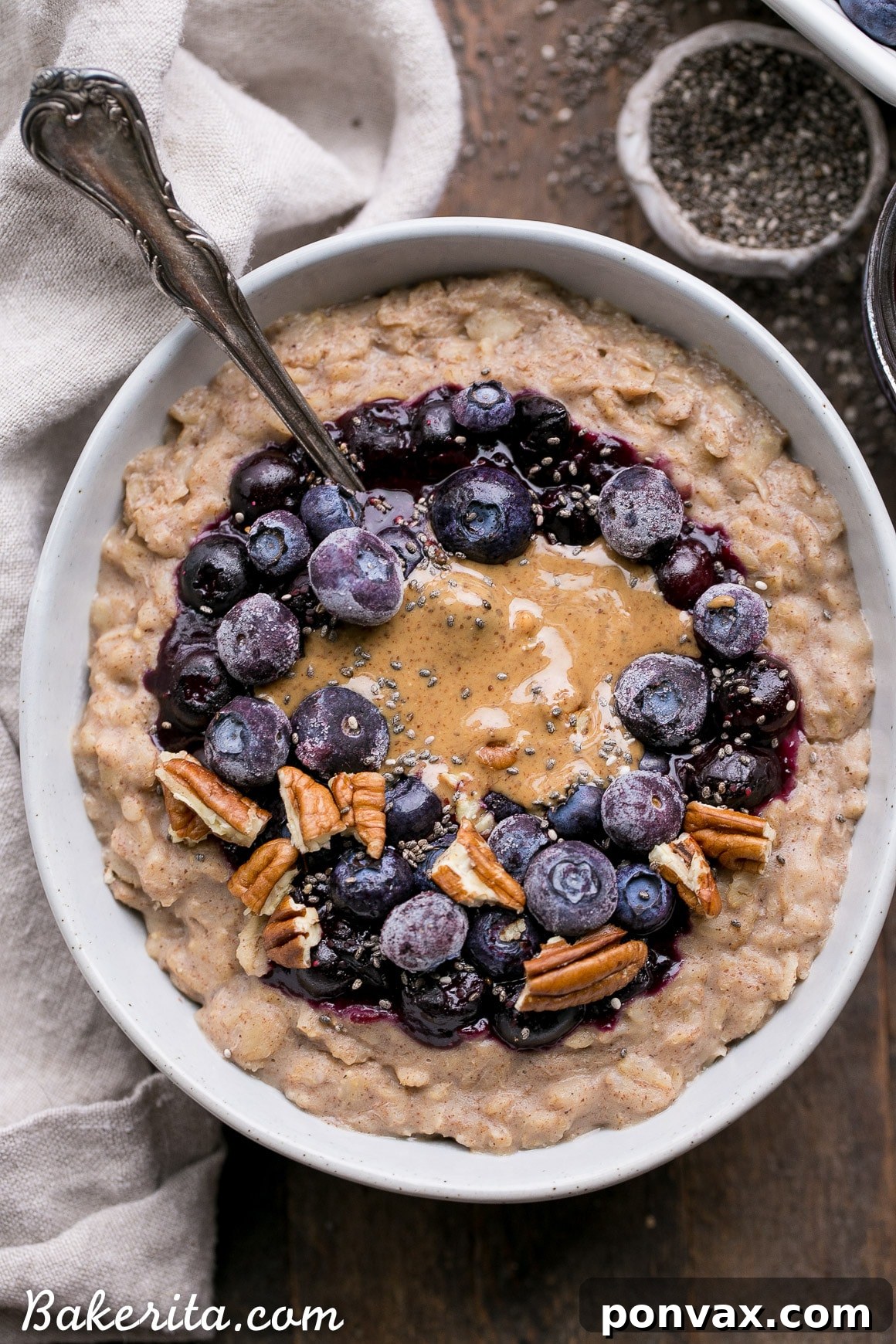 A spoonful of blueberry muffin oatmeal being lifted from a bowl, showing its creamy texture and blueberry topping.