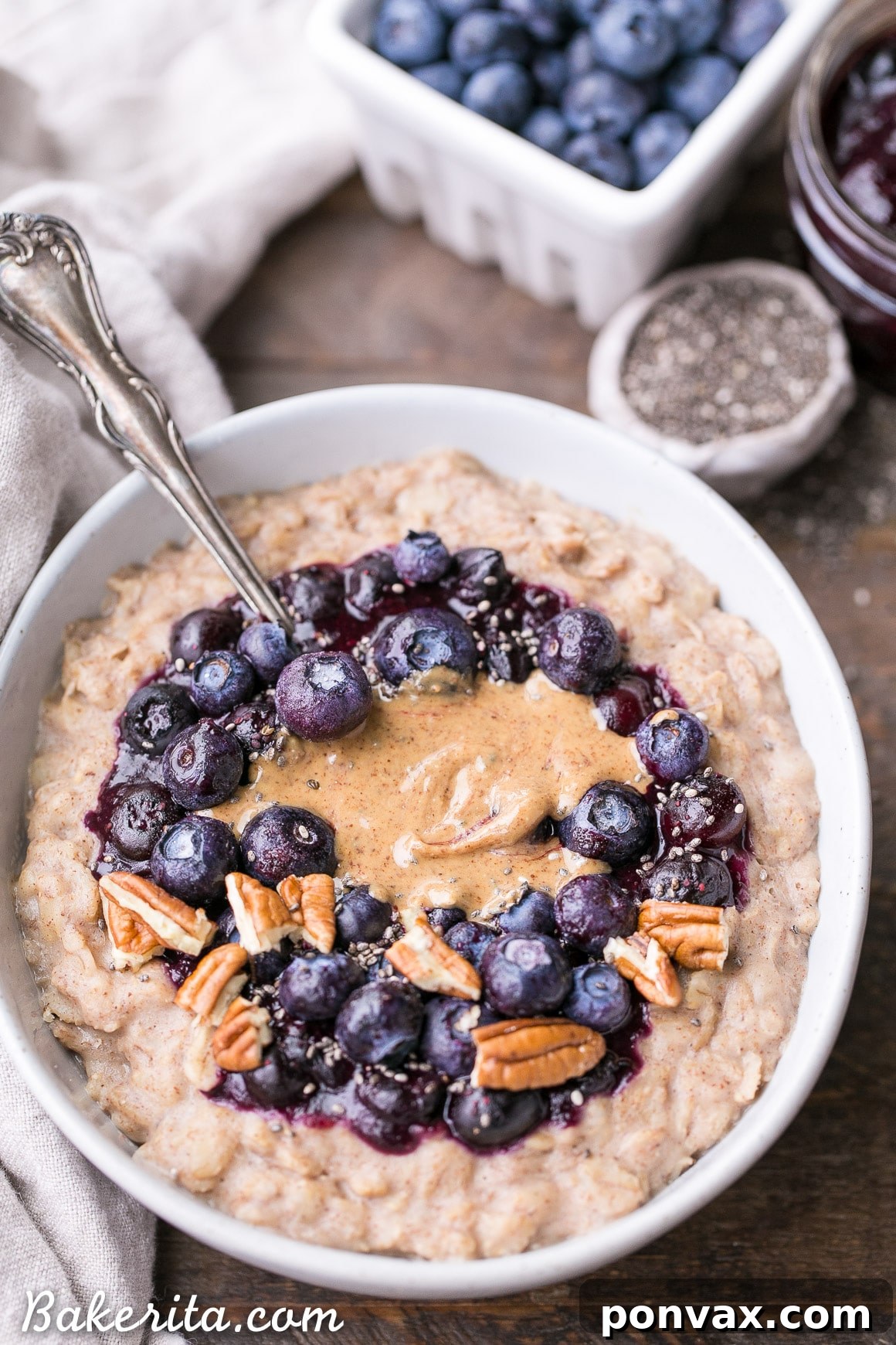 A bowl of creamy gluten-free blueberry muffin oatmeal with various toppings like nuts, seeds, and fresh berries.