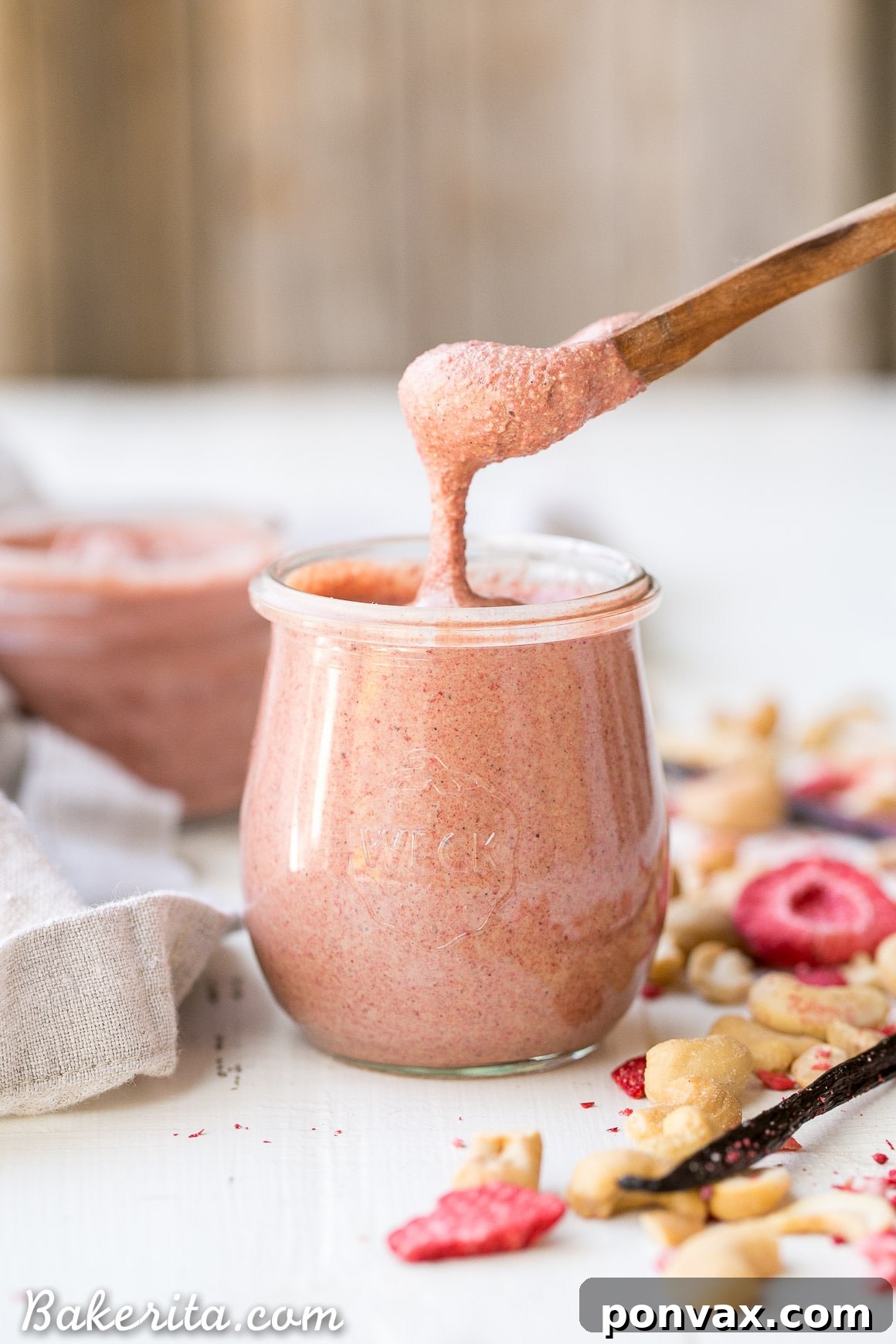 Ingredients for Strawberry Cashew Butter laid out: raw cashews, a bag of freeze-dried strawberries, and vanilla bean powder.