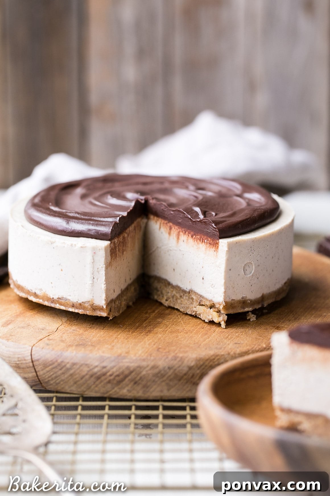 Pure Vanilla Bliss: No-Bake Cheesecake for All 3 Close-up of a No-Bake Vanilla Bean Cheesecake slice, showcasing its creamy cashew filling, walnut crust, and generous chocolate ganache topping. A perfect gluten-free, Paleo, and vegan treat.