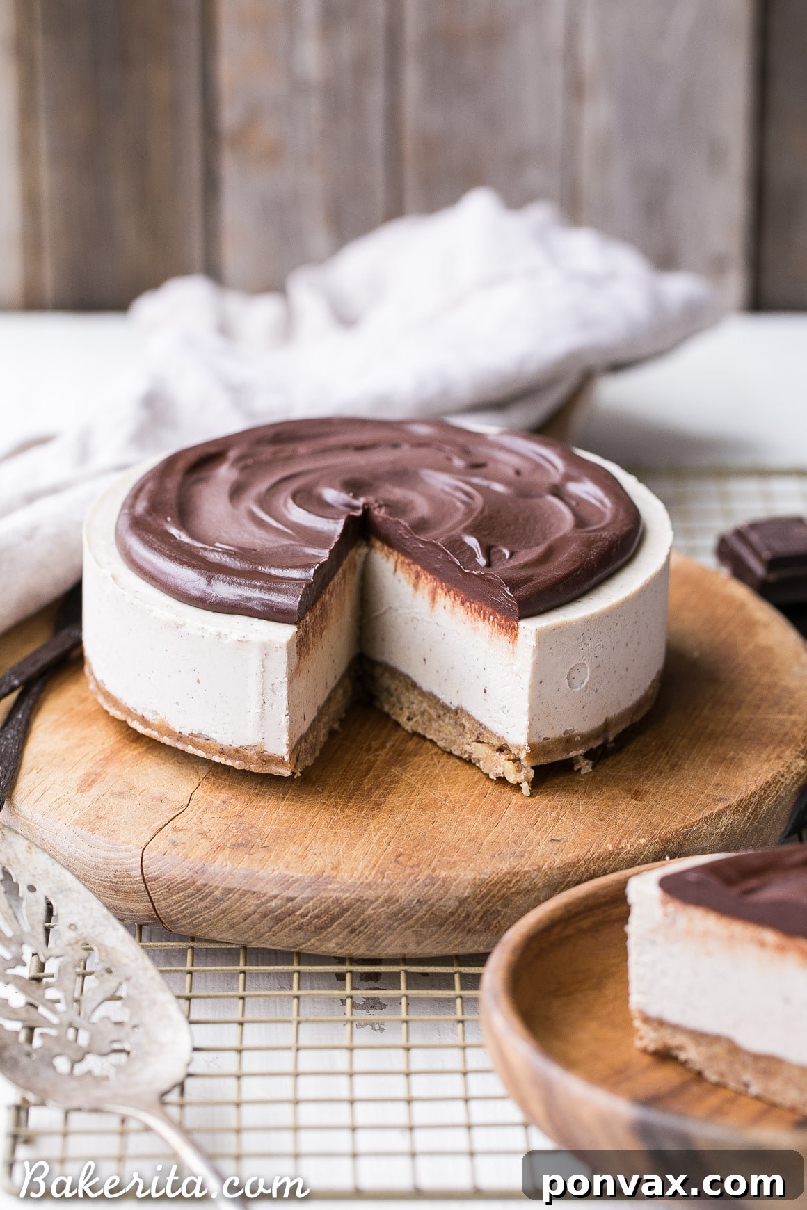 Pure Vanilla Bliss: No-Bake Cheesecake for All 6 A whole No-Bake Vanilla Bean Cheesecake with chocolate ganache, garnished with fresh vanilla beans, showcasing its elegant and simple beauty. This is a gluten-free, Paleo, and vegan dessert.