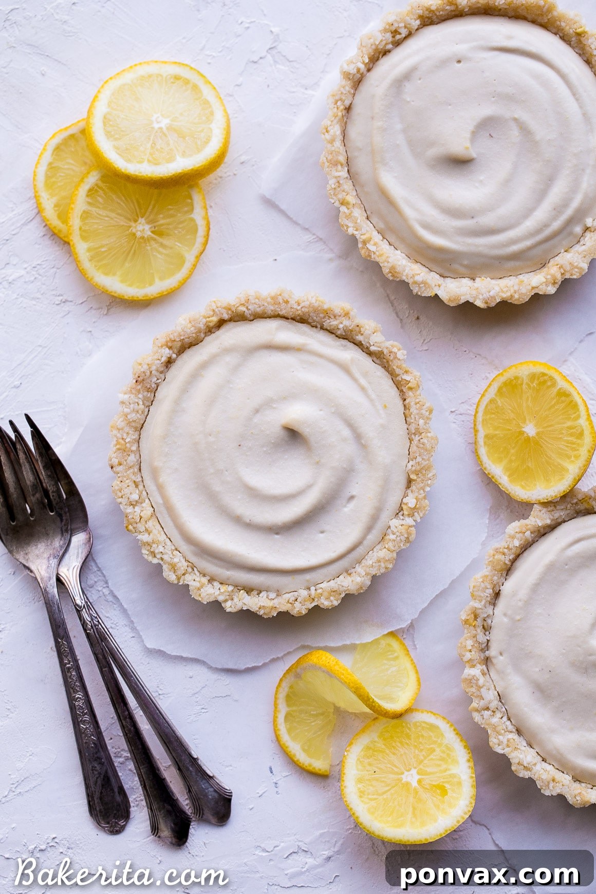 Creamy Vegan No-Bake Lemon Tarts 4 Individual No-Bake Lemon Tart, garnished with lemon zest and a sprig of mint, ready to be served.