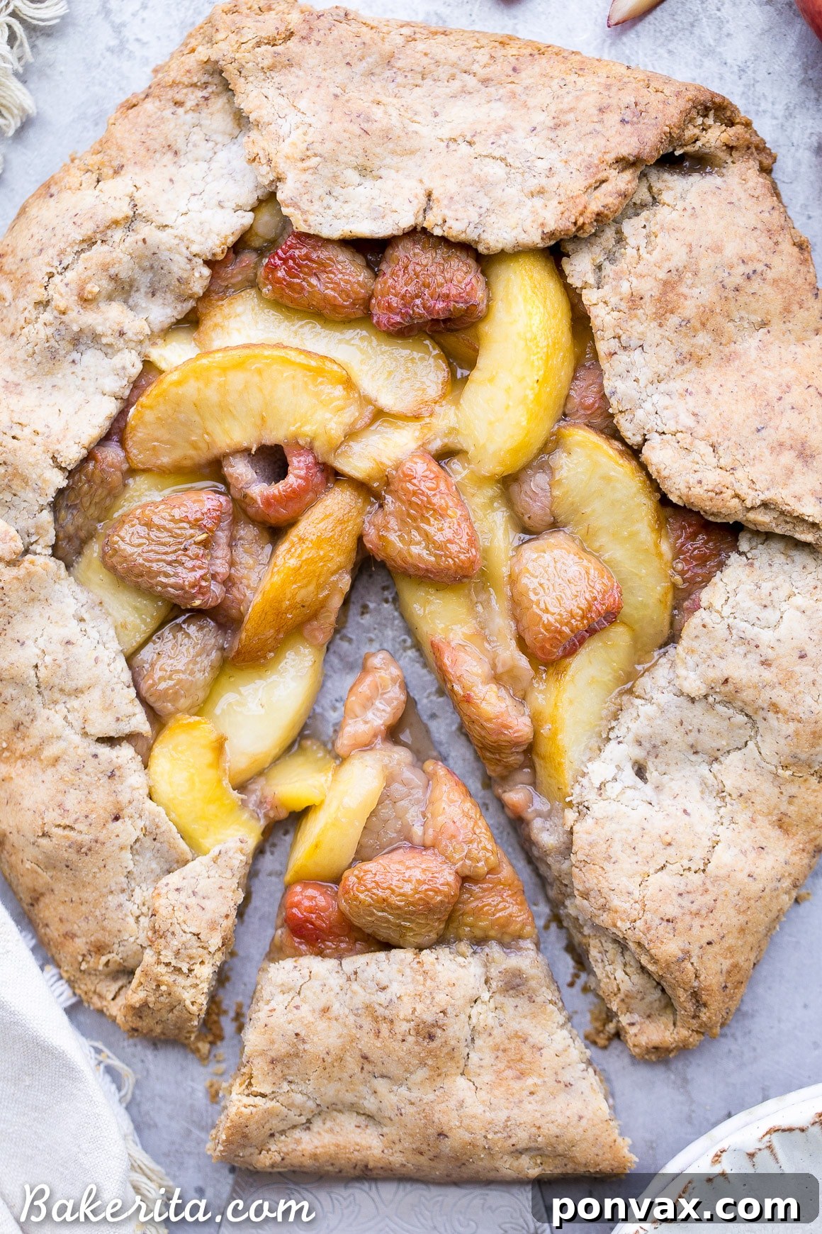 A freshly baked Vegan Peach Raspberry Galette cooling on a wire rack, featuring a perfectly golden crust and a glistening, bubbly fruit center.