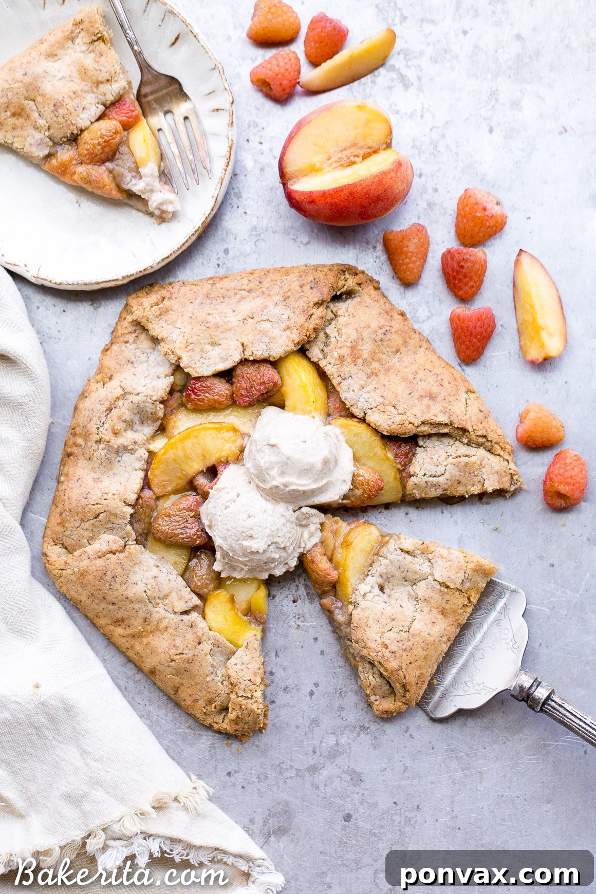 A slice of Vegan Peach Raspberry Galette served with a scoop of vegan vanilla ice cream, showcasing the flaky crust, juicy fruit filling, and perfect golden color.