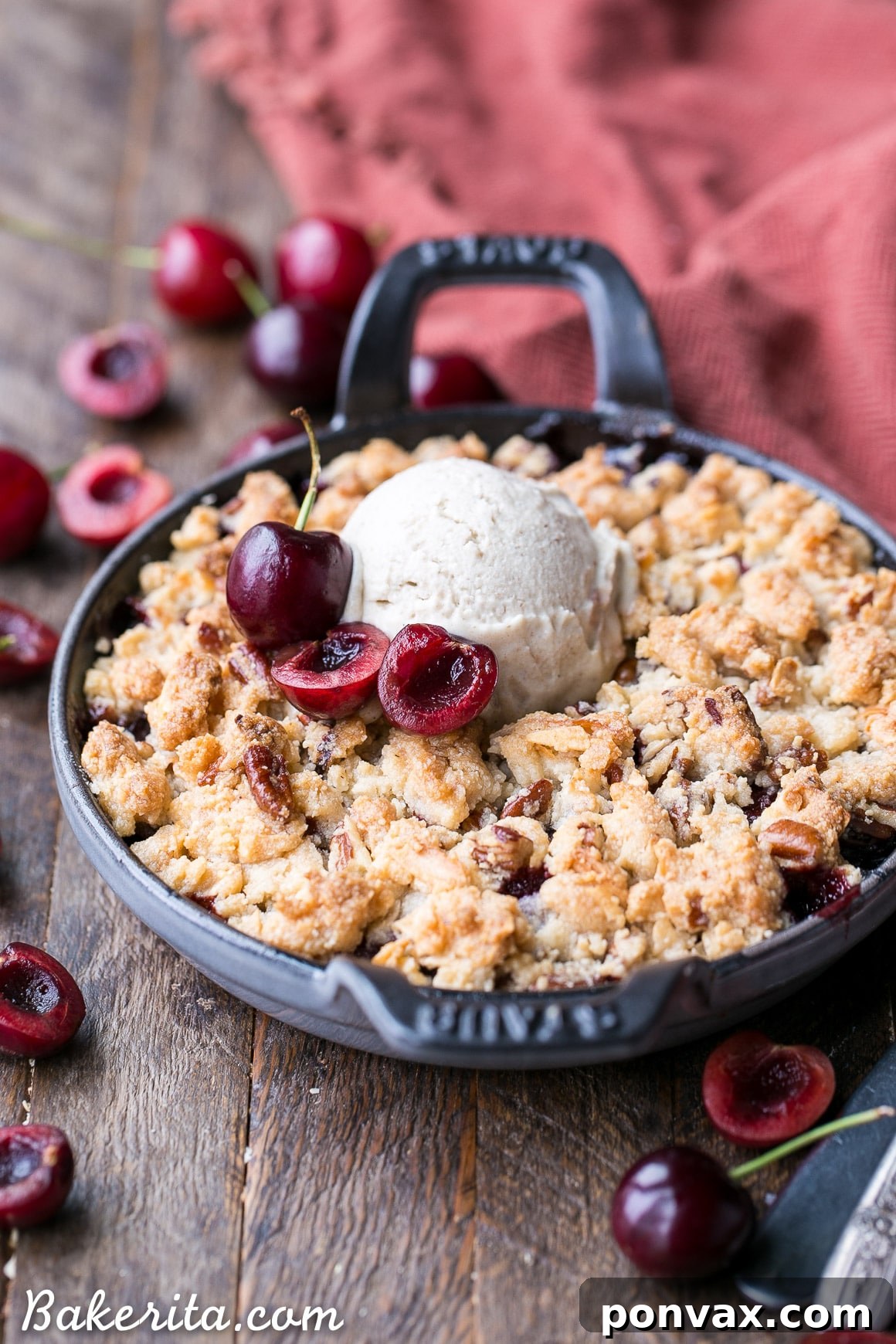 A serving of grain-free cherry crisp topped with a dollop of whipped cream or ice cream, showing the rich cherry filling and the golden, crumbly topping.