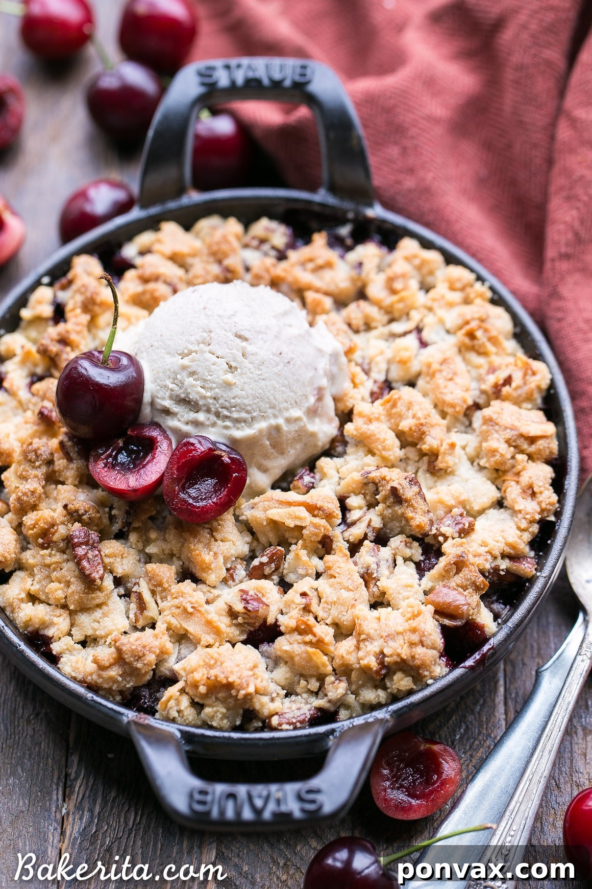 A close-up of a baking dish filled with raw cherry crisp ingredients, showing the vibrant cherry filling and the prepared grain-free crumble topping before baking.