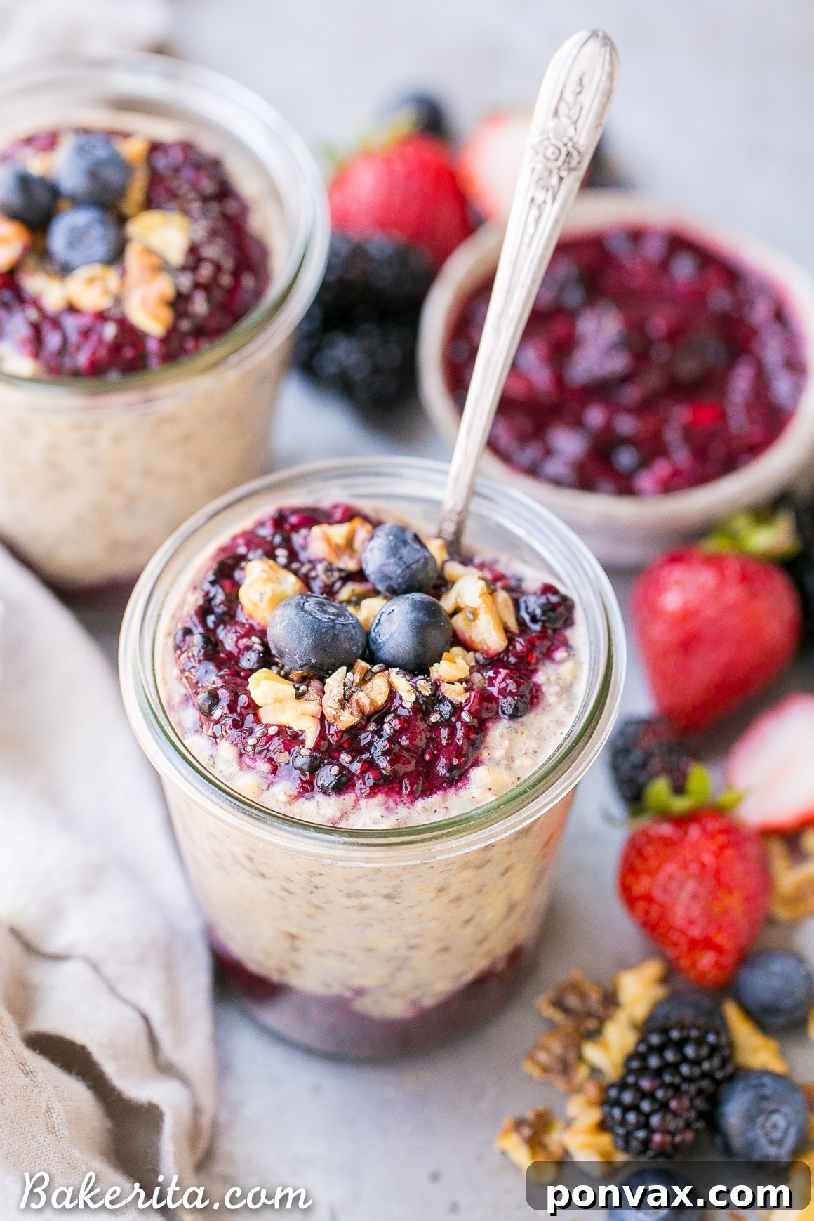 A beautifully presented jar of Superfood Overnight Oats topped with vibrant Berry Chia Jam and fresh berries.