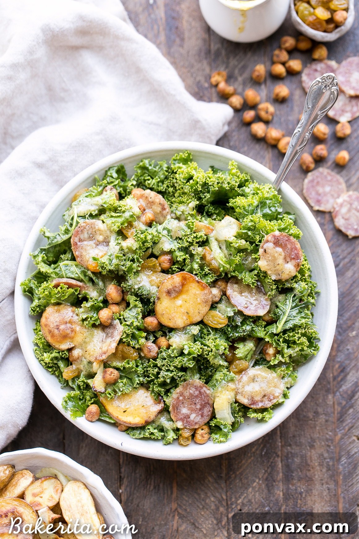 A vibrant Kale & Salami Salad with Roasted Garlic Vinaigrette, featuring roasted fingerling potatoes, crispy toasted chickpeas, golden raisins, and caramelized onions, perfect for a healthy and delicious meal.