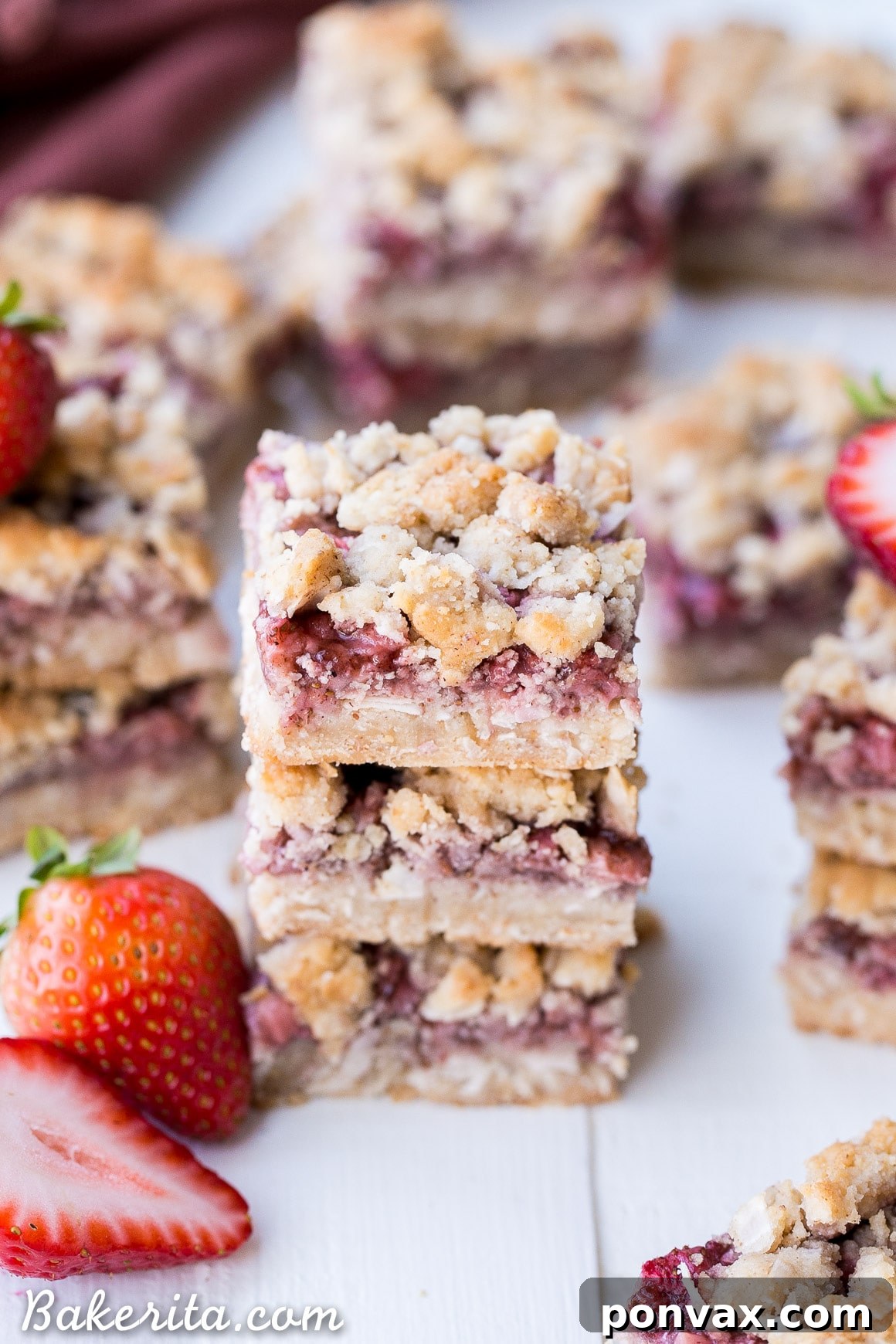 Several Strawberry Crumble Bars arranged on a white serving plate, garnished with fresh mint.