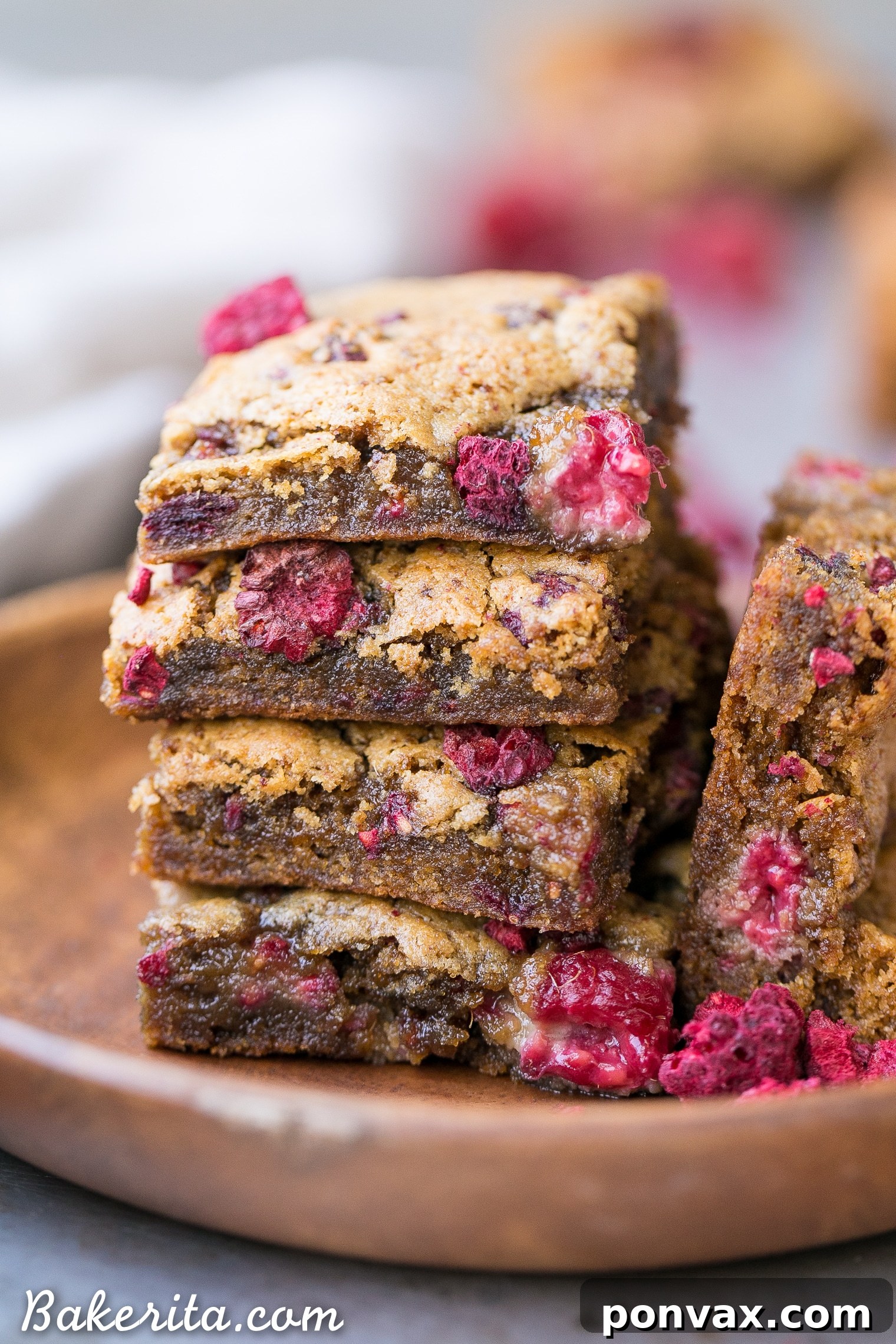 Several squares of vegan raspberry blondies arranged beautifully, highlighting the golden-brown edges and scattered fresh raspberries.