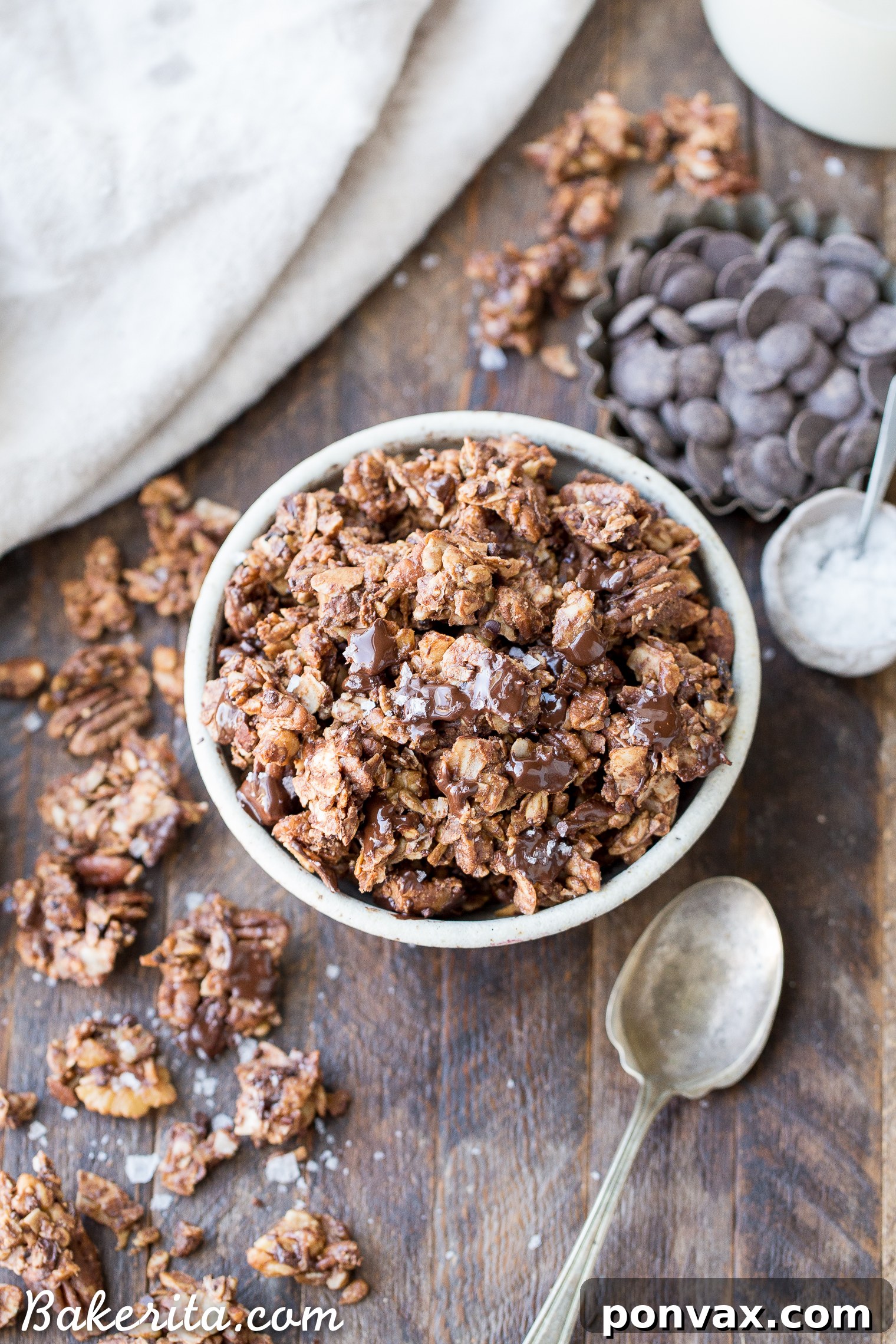Freshly baked grain-free granola with chopped dark chocolate sprinkled generously on top, melting into the warm clusters.