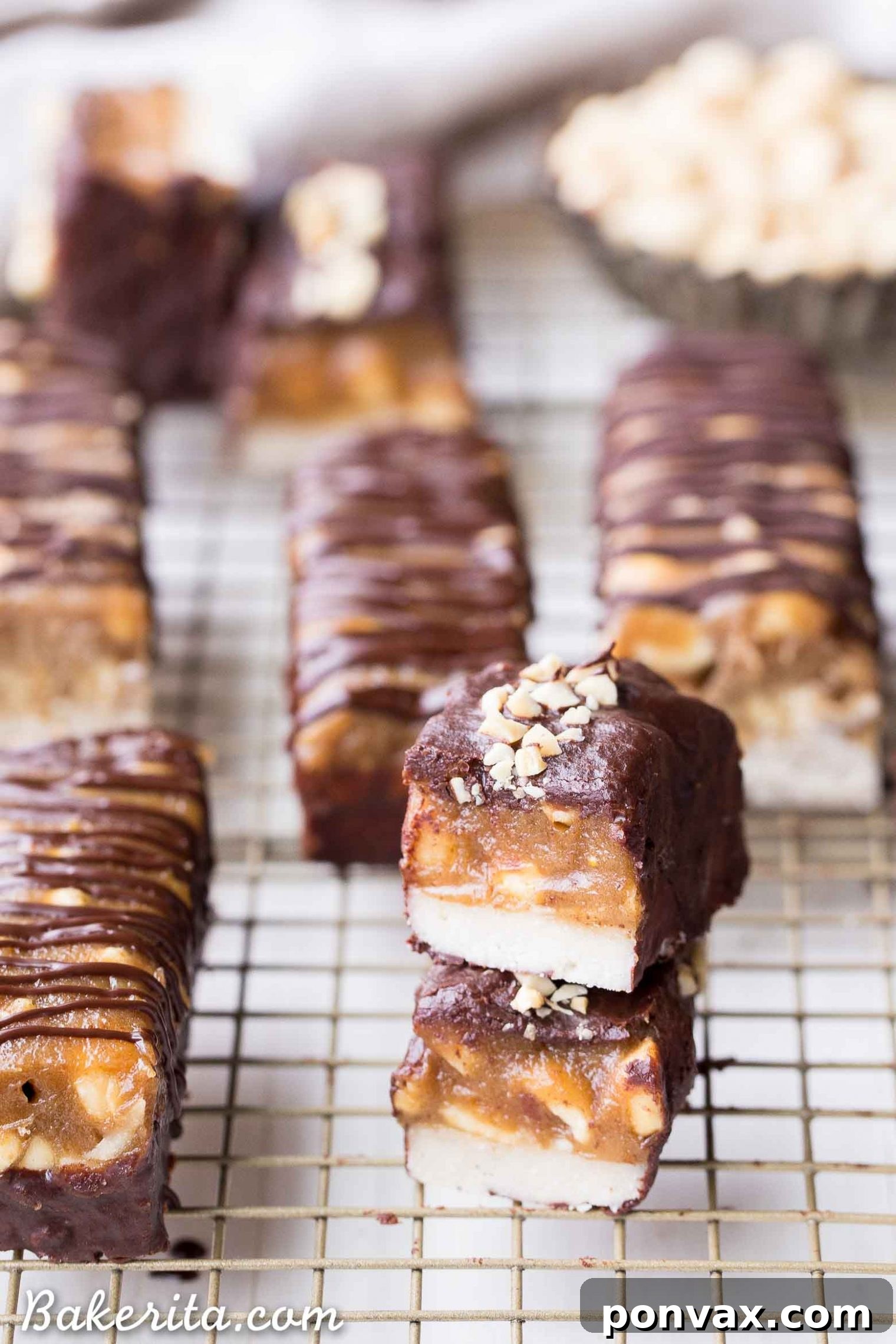 Homemade Snickers bars laid out on parchment paper, ready for their chocolate coating.