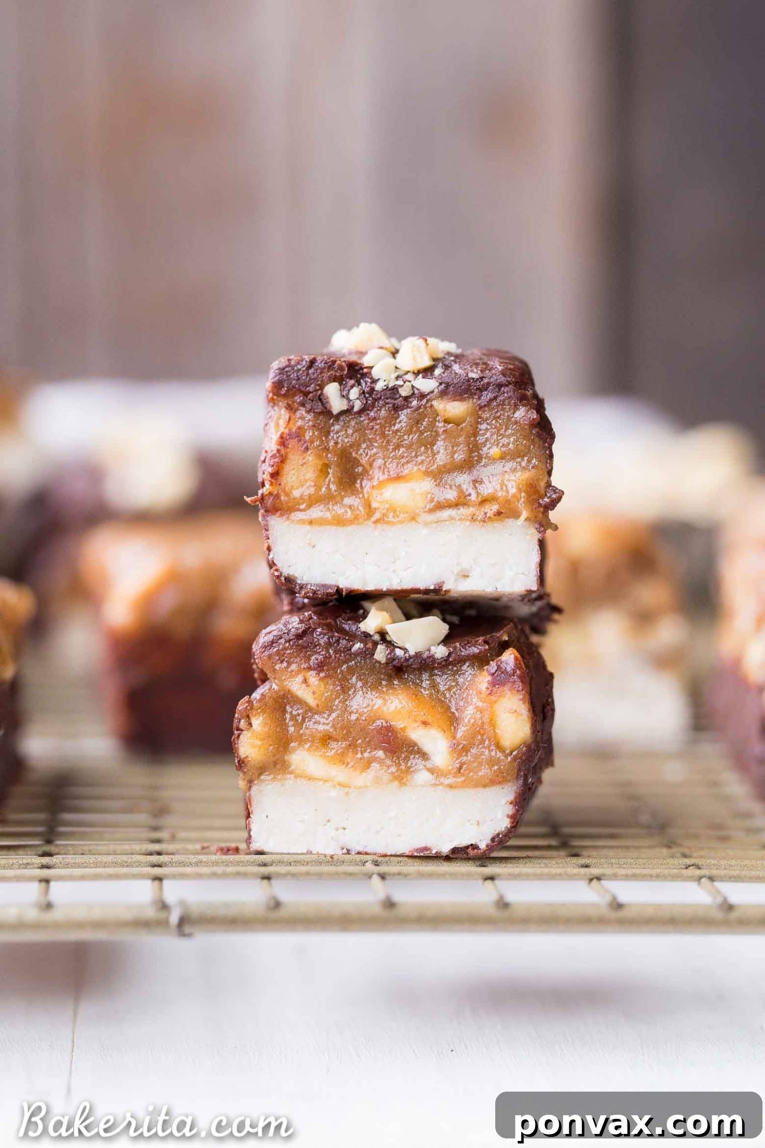 A stack of finished homemade Snickers bars, showing their delicious multi-layered structure and chocolate coating.