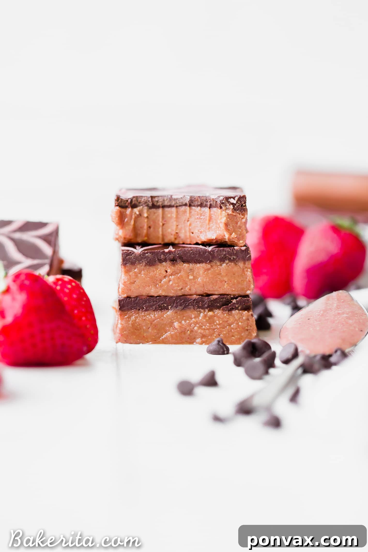 Overhead view of the No-Bake Chocolate Strawberry Cashew Butter Bars with the chocolate topping, before the strawberry drizzle is applied. The contrast of the dark chocolate against the light pink base is striking.