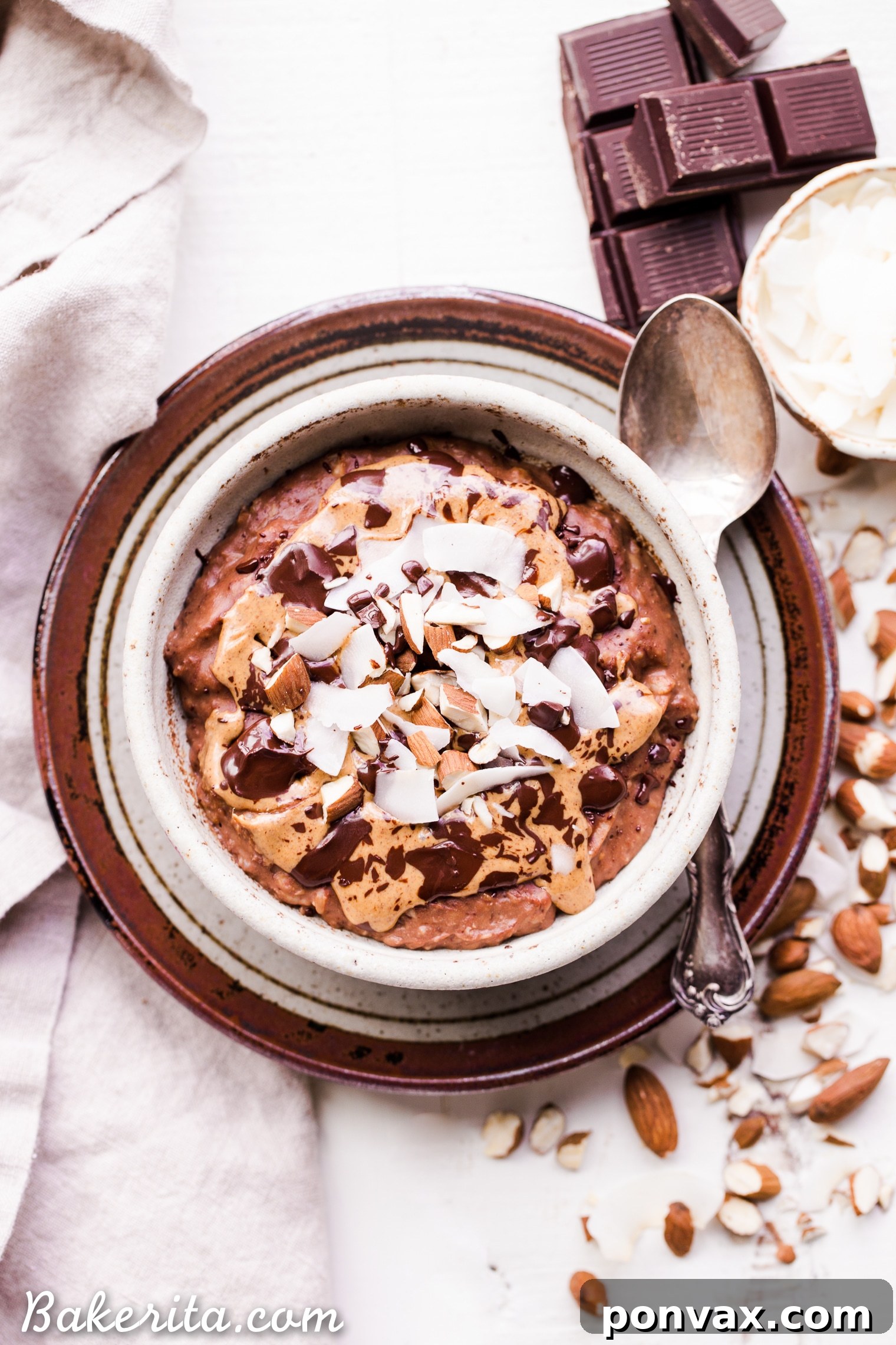A beautifully presented bowl of creamy Almond Joy Oatmeal, garnished with toasted coconut flakes, whole almonds, and melted dark chocolate, ready to be enjoyed.