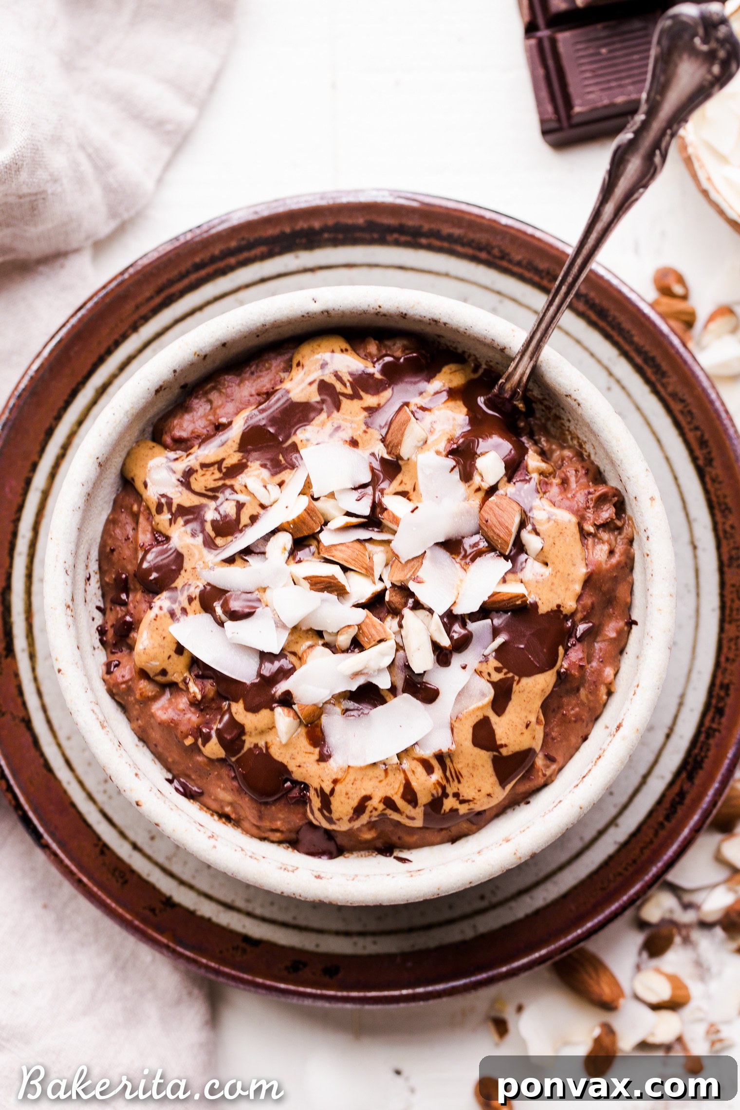 Close-up shot of creamy chocolate oatmeal simmering in a small saucepan, with hints of mashed banana and shredded coconut visible.