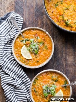 Creamy Vegan Red Lentil Delight 7 Two bowls of Vegan Red Lentil Soup topped with microgreens and lemon, with a striped napkin. Also a pot of healthy lentil soup next to the bowls!