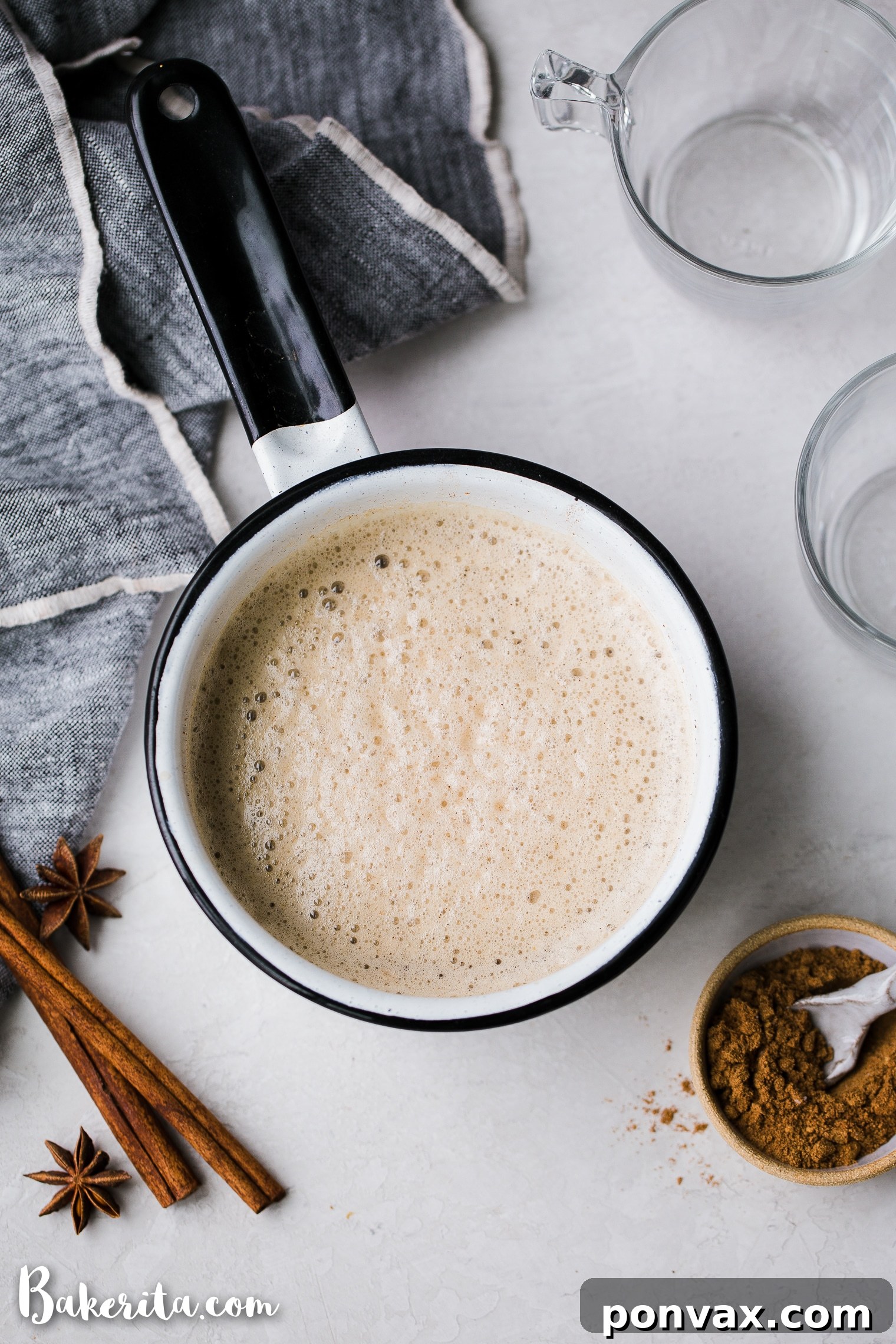 Close-up of a frothy Vegan Chai Latte in a clear glass mug, showcasing its rich color and inviting texture, with steam gently rising, emphasizing its warmth.