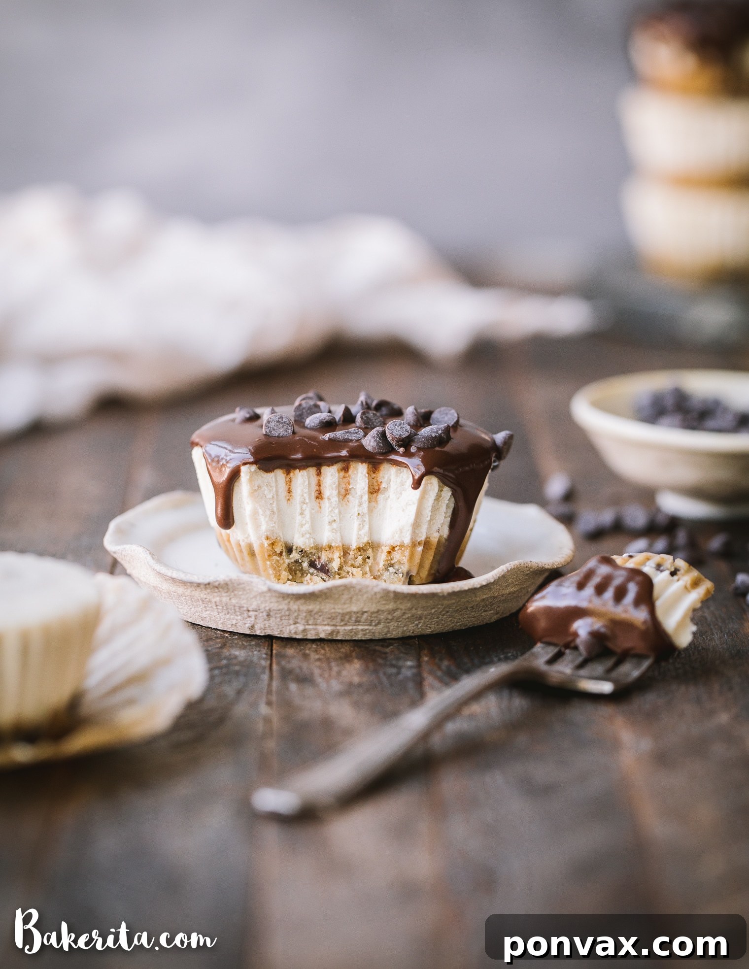Close-up of a mini No-Bake Vegan Chocolate Chip Cookie Dough Cheesecake, showing the layers of cookie dough crust, creamy cashew filling, and chocolate ganache.