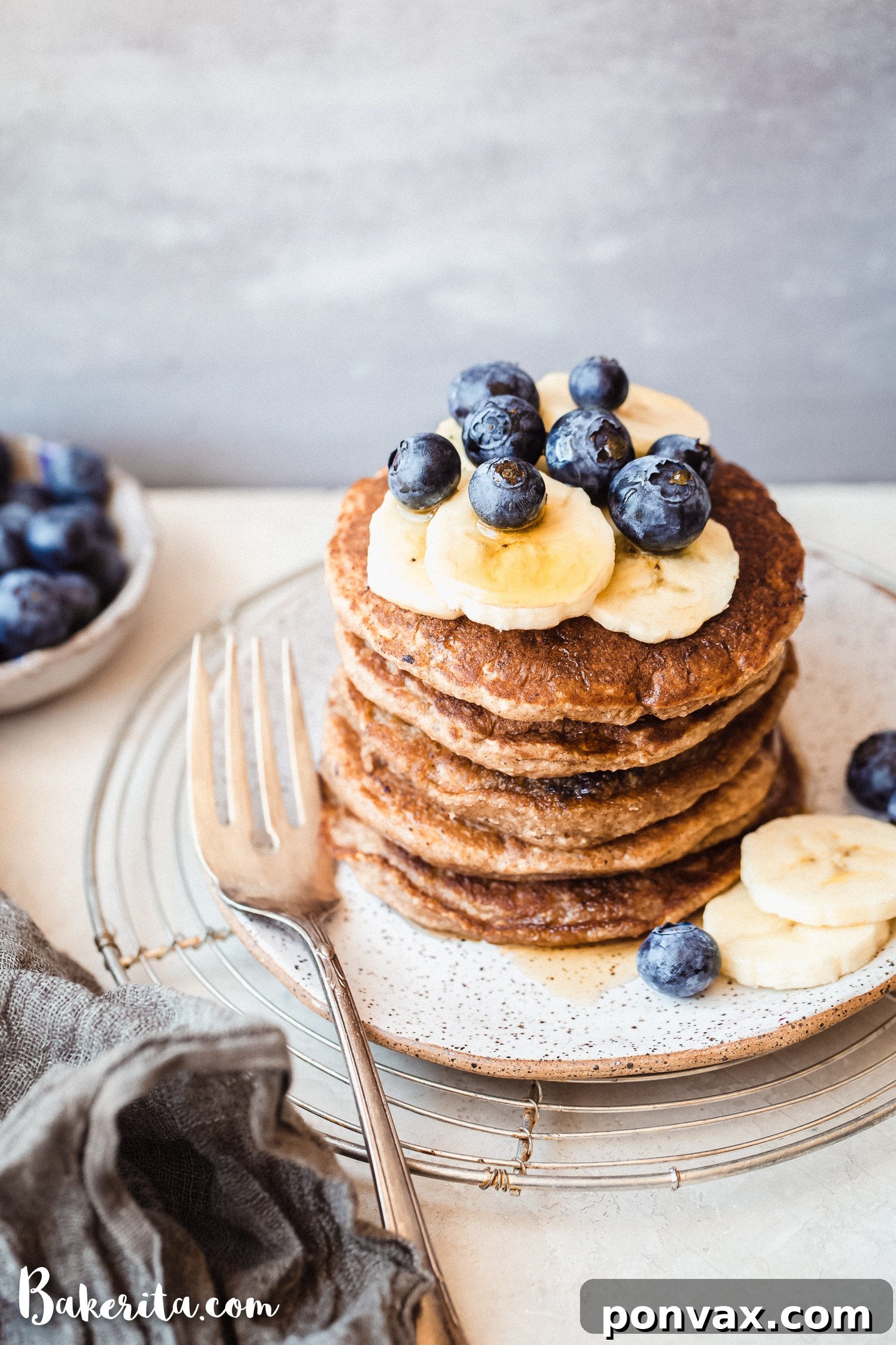 Uncooked gluten-free vegan banana blueberry pancake batter being poured onto a hot griddle, ready to cook.