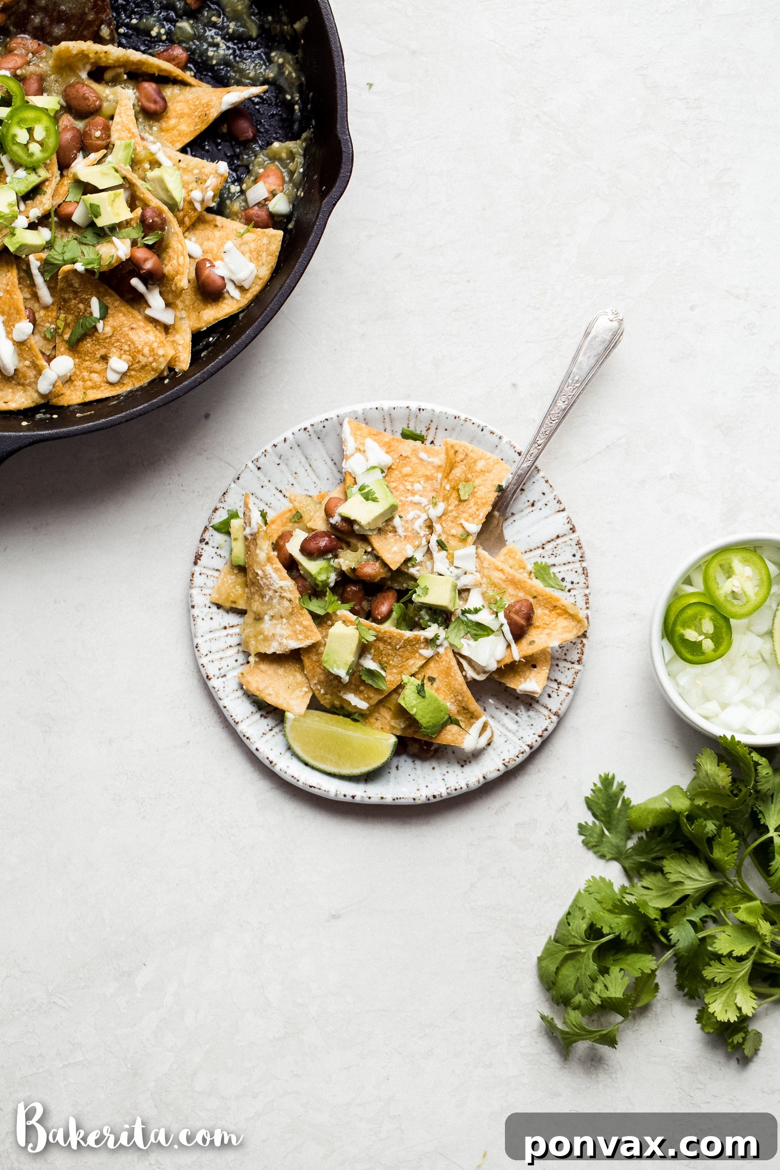 A vibrant bowl of Vegan Chilaquiles Verdes with green salsa, tortilla chips, avocado, and cilantro, served with lime wedges.