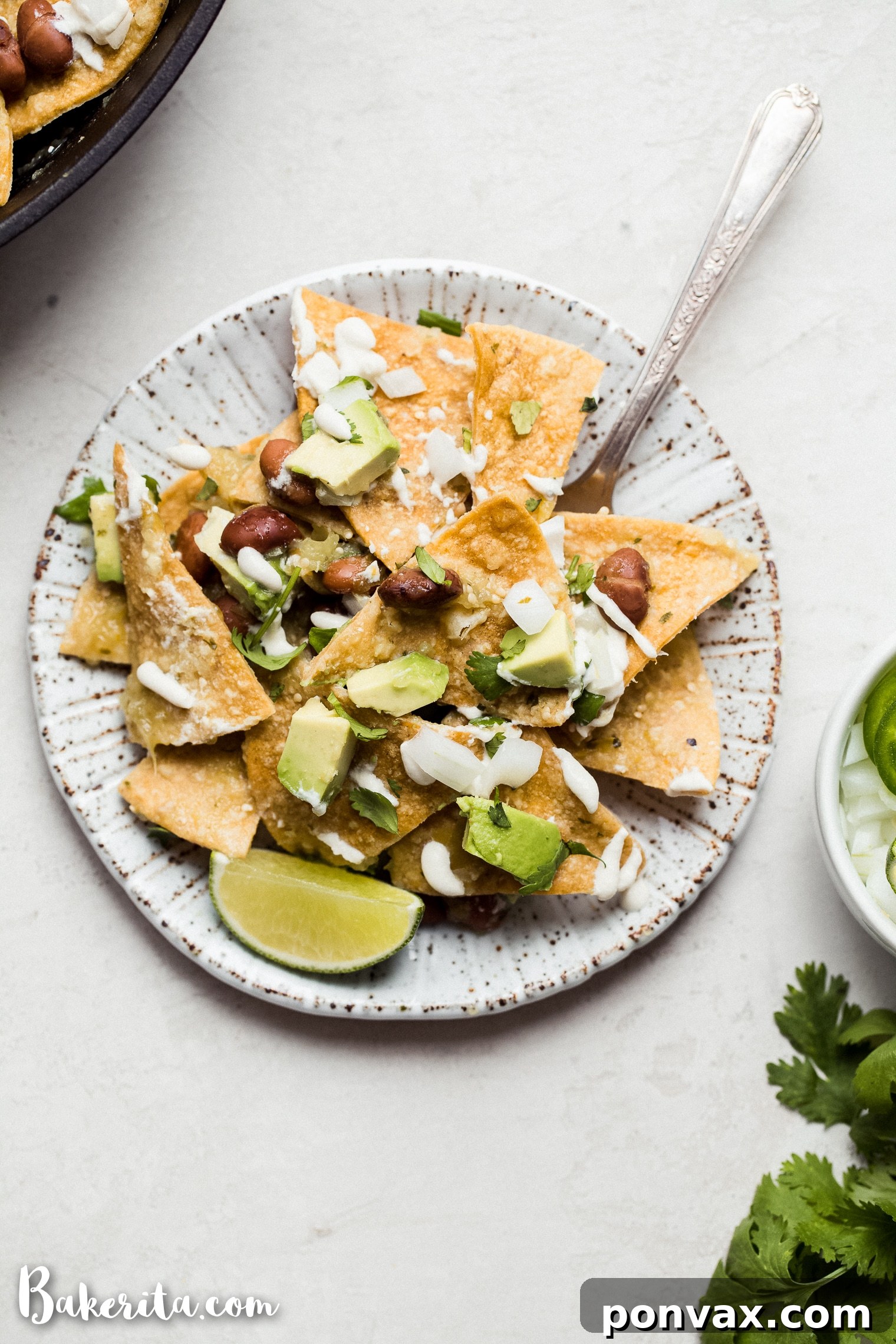 A smooth, creamy vegan sour cream in a glass bowl, ready to be drizzled over dishes, with limes in the background.