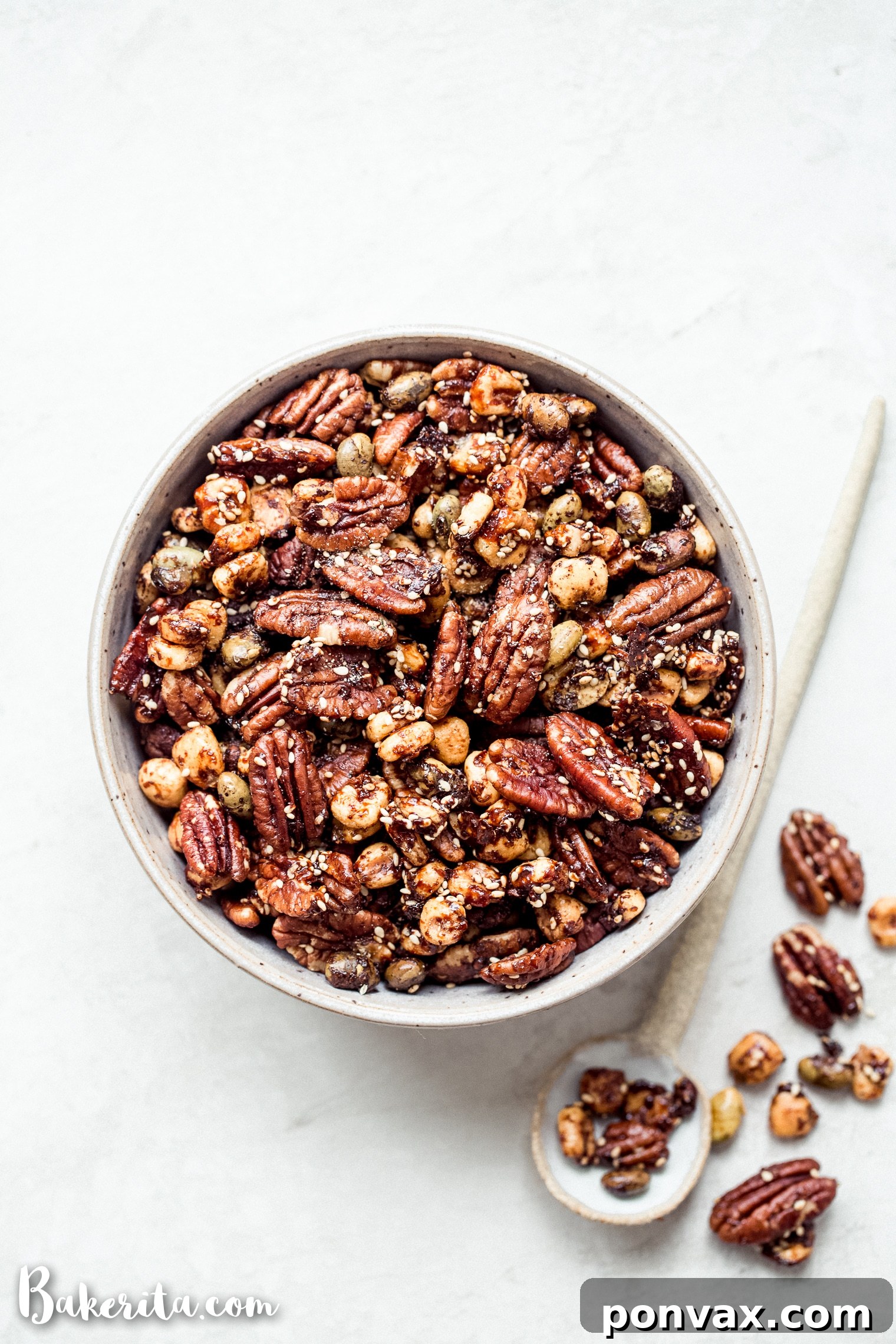 Freshly baked Sesame Tamari Pecan Snack Mix cooling on a parchment-lined baking sheet, displaying its appealing texture and golden sheen.