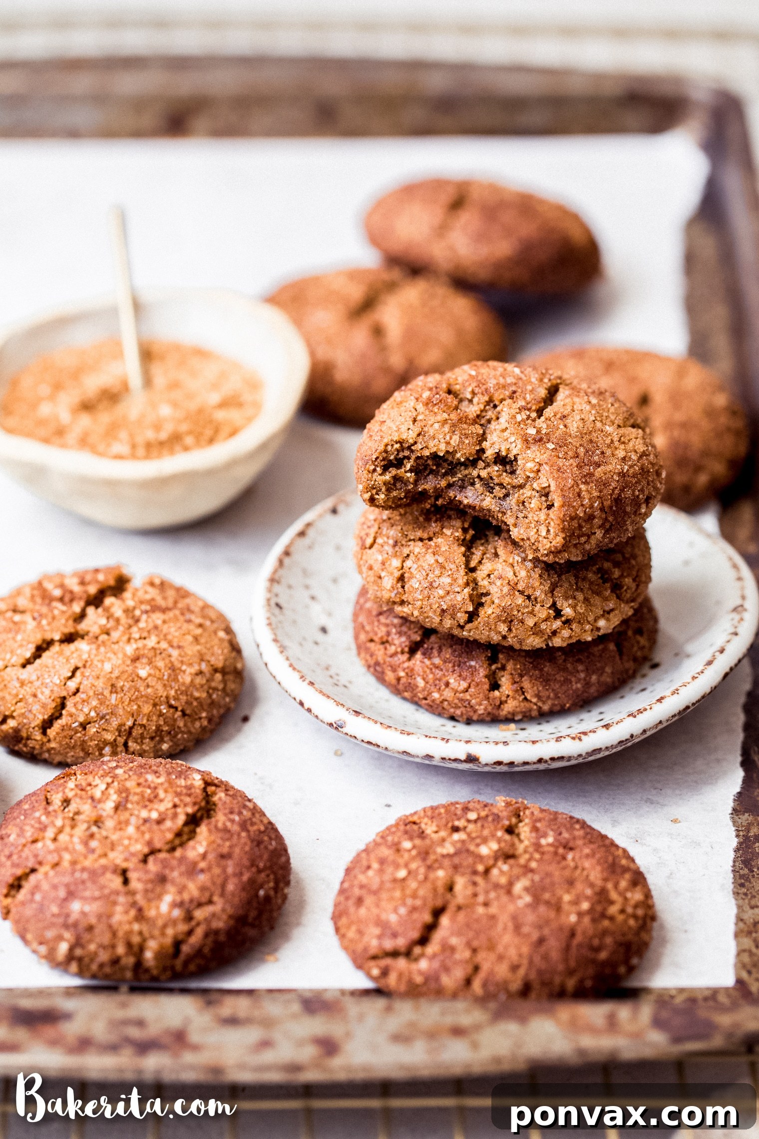 Freshly baked gluten-free vegan snickerdoodles cooling on a parchment-lined baking sheet.