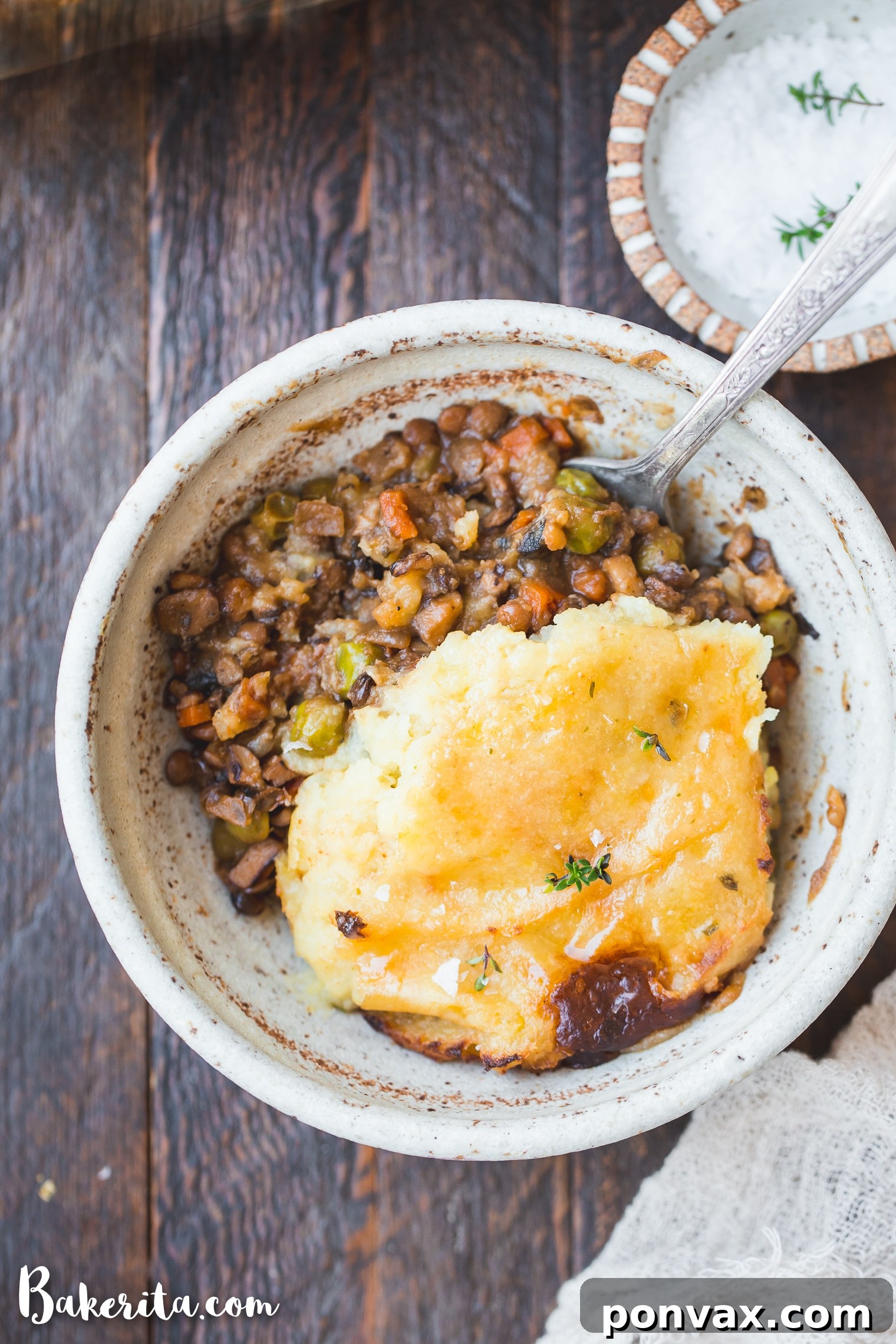 A generous serving of Vegan Shepherd's Pie on a plate, showing the layers of lentil filling and mashed potatoes, garnished with fresh herbs.