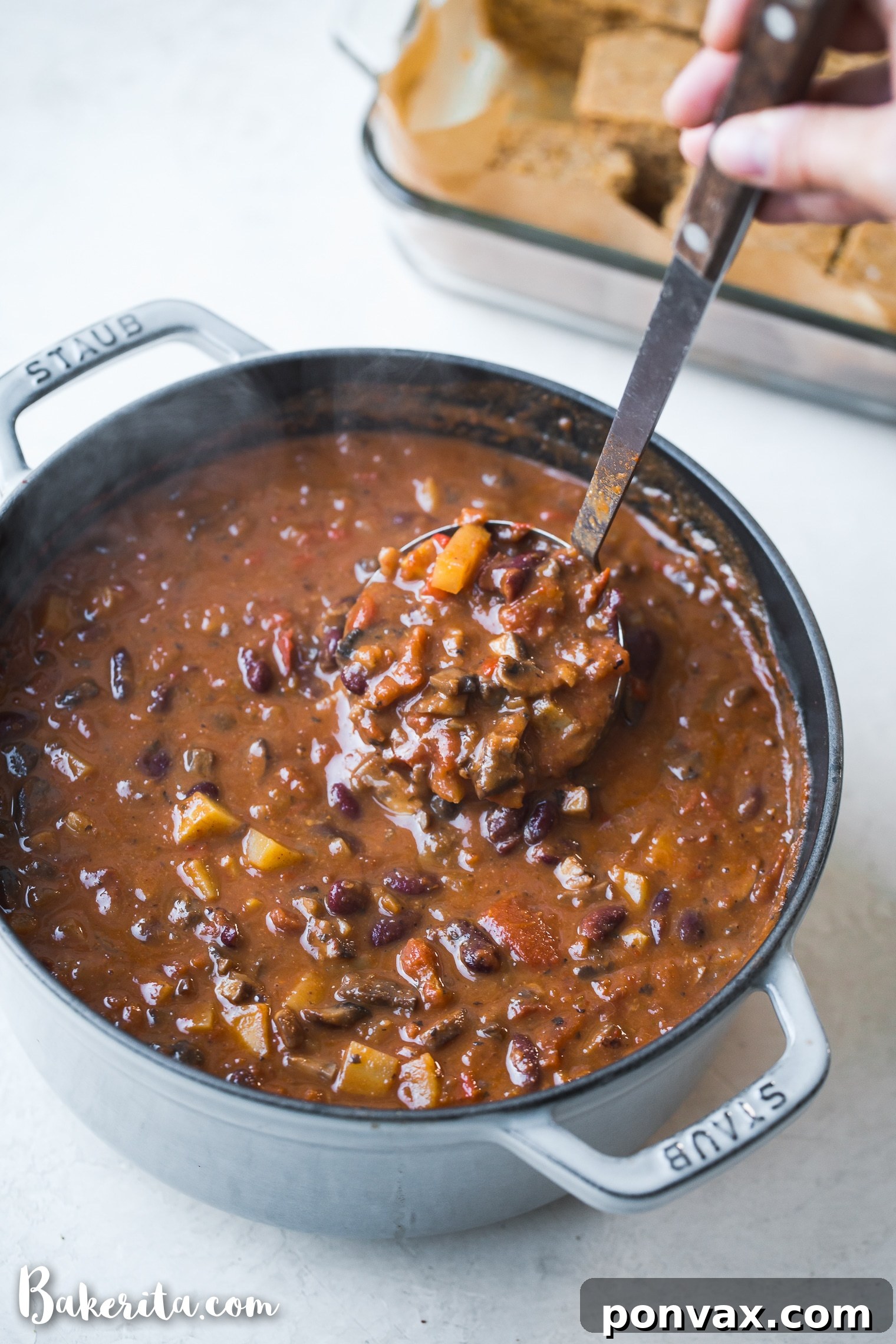 Close-up of the rich, deep red color of the vegan chili, showing visible chunks of vegetables and beans.