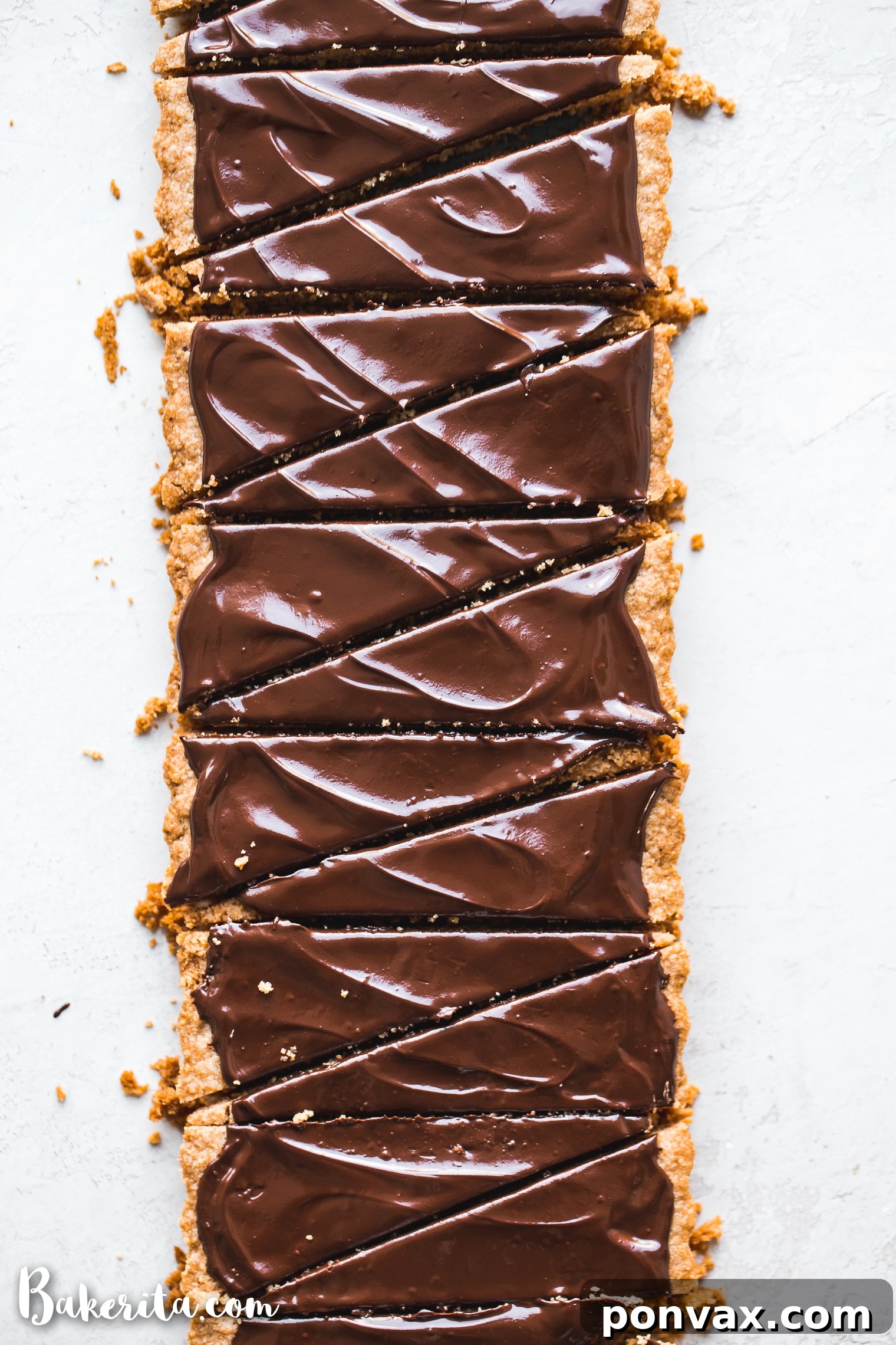 Gluten-free vegan shortbread squares topped with melted dark chocolate, presented on a white plate.