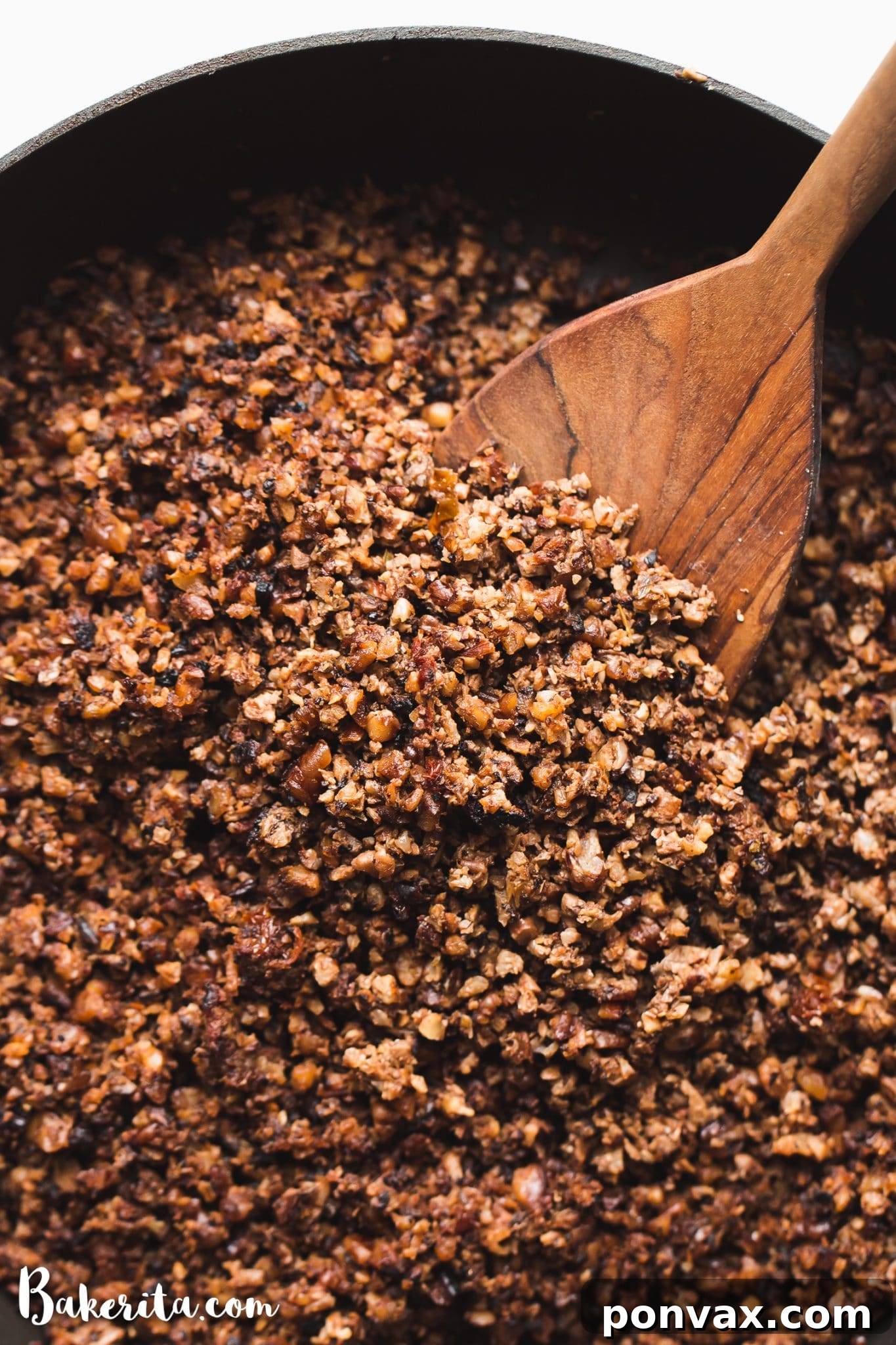 This flavorful plant-based taco meat recipe is a game-changer! It’s made with cauliflower, mushrooms, nuts, and spices. Vegan ground meat filling is in a black cast iron pan with a wooden spoon, ready to be served.