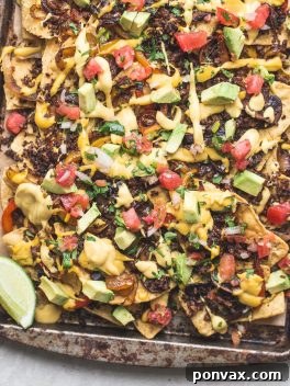 A large platter of the best vegan nachos, loaded with vibrant toppings and cheese sauce.