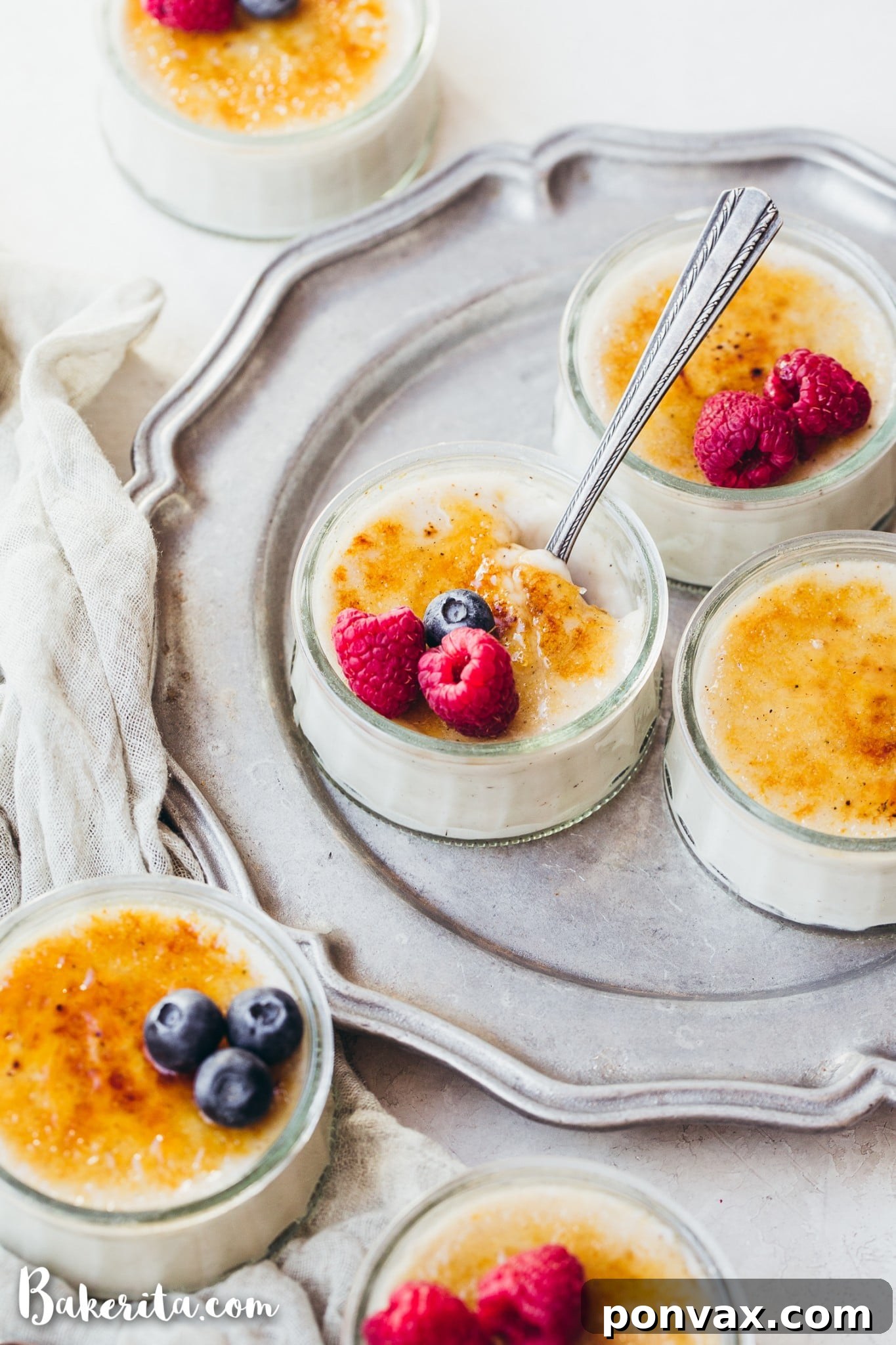 Ingredients for Vegan Creme Brulee laid out on a table, including coconut milk cans, maple syrup, and vanilla bean powder.