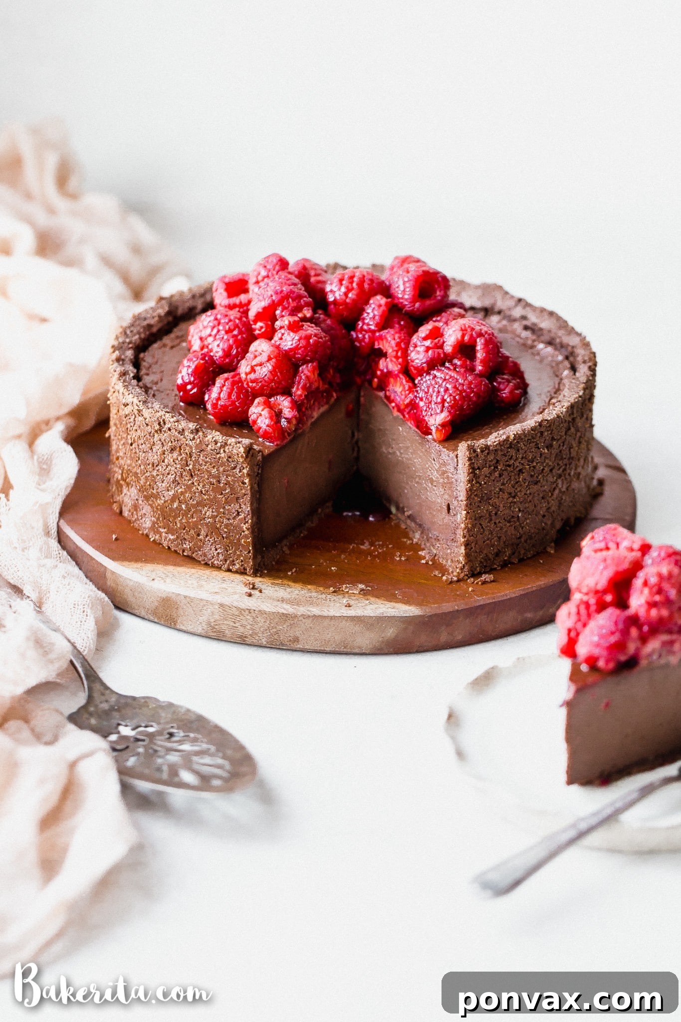 A slice of Baked Vegan Chocolate Cheesecake garnished with fresh raspberries, showcasing its creamy texture and rich chocolate color.