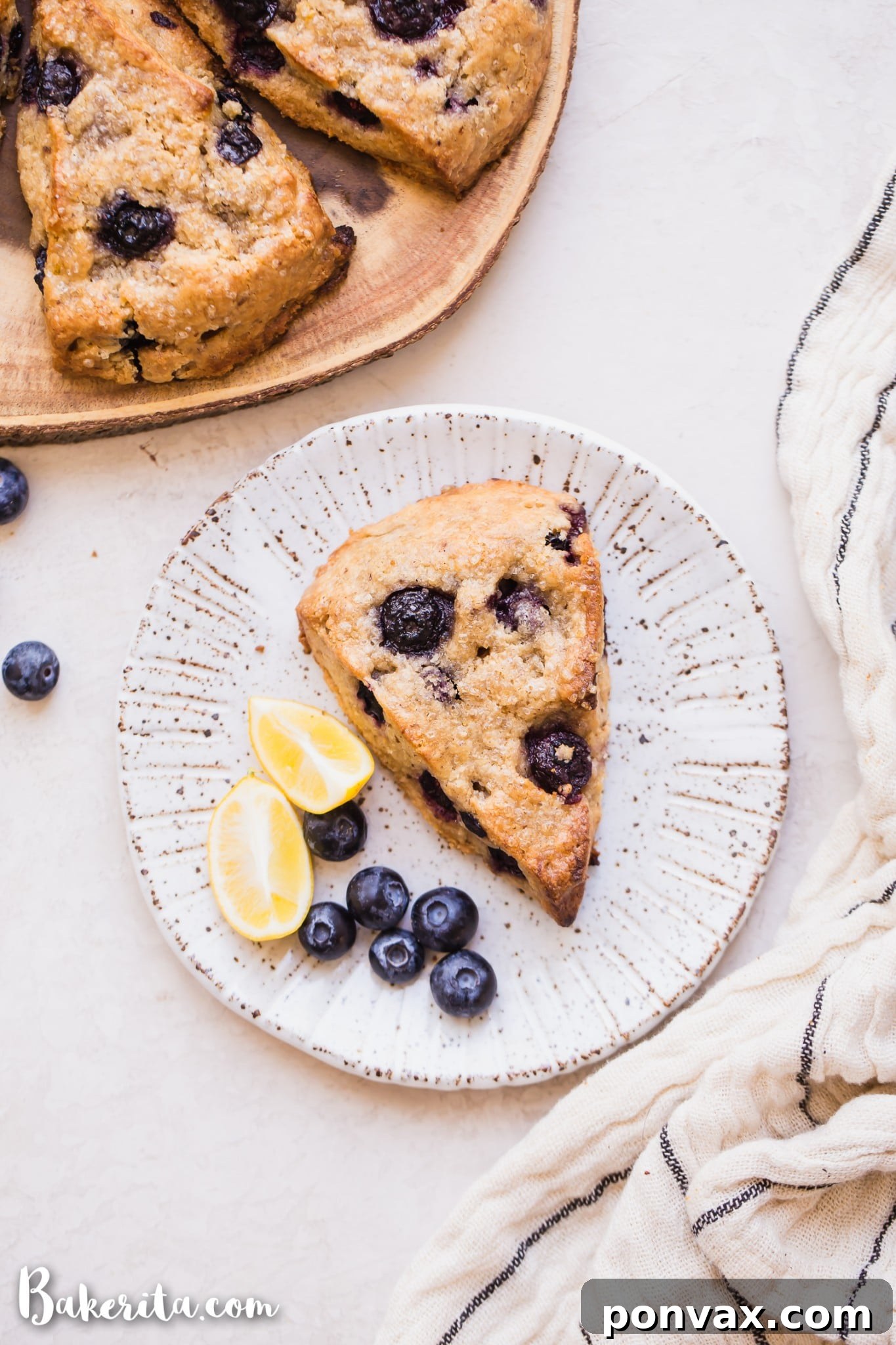 Freshly baked gluten-free vegan lemon blueberry scones, golden brown with a crispy exterior and tender texture, garnished with lemon zest and fresh blueberries.