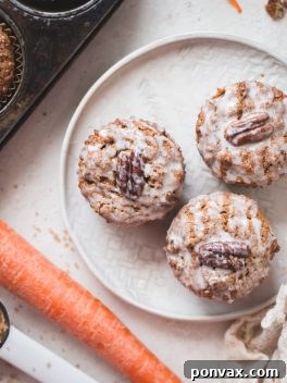 A final close-up of a single Gluten-Free Vegan Carrot Cake Muffin, drizzled with a light glaze, on a white background.
