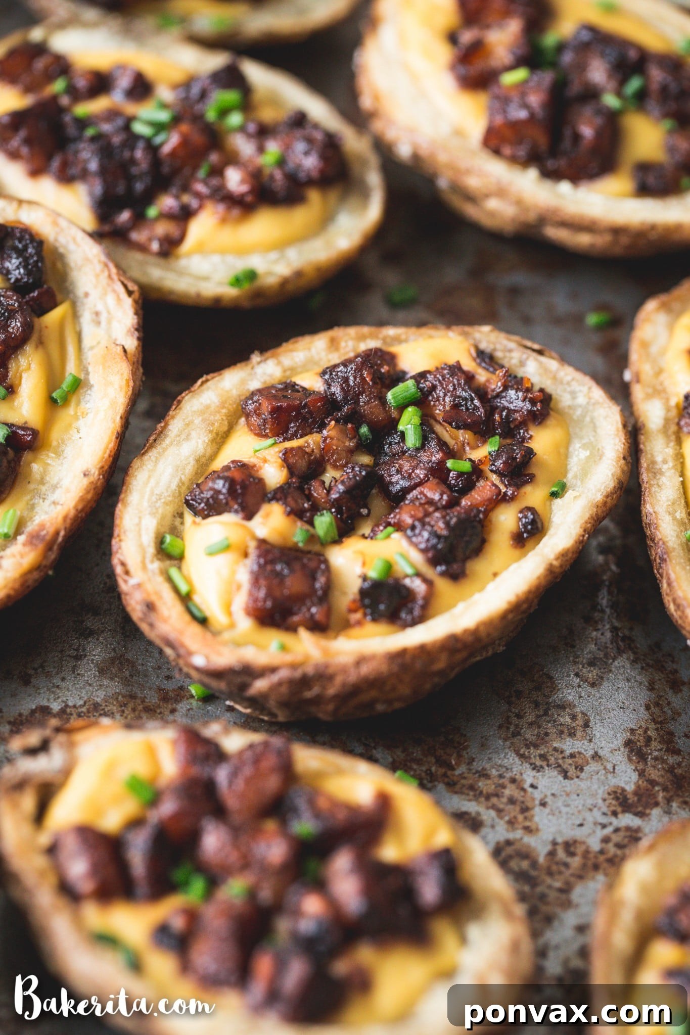 A close-up of a single vegan potato skin, showcasing the crispy potato, melted vegan cheese, and tempeh bacon. 