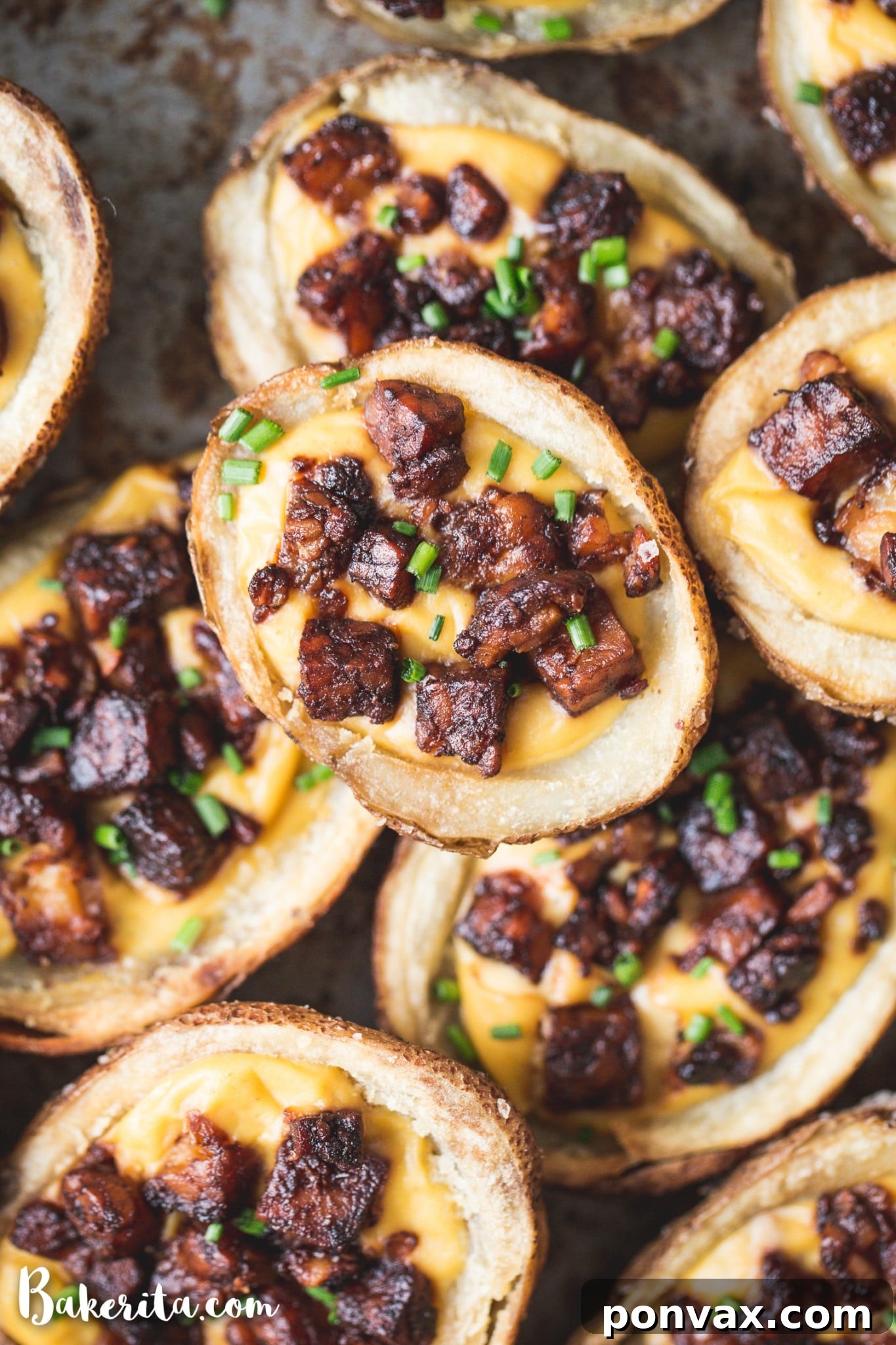 Ingredients for vegan potato skins laid out on a table: potatoes, tempeh, cheese sauce, and various spices.