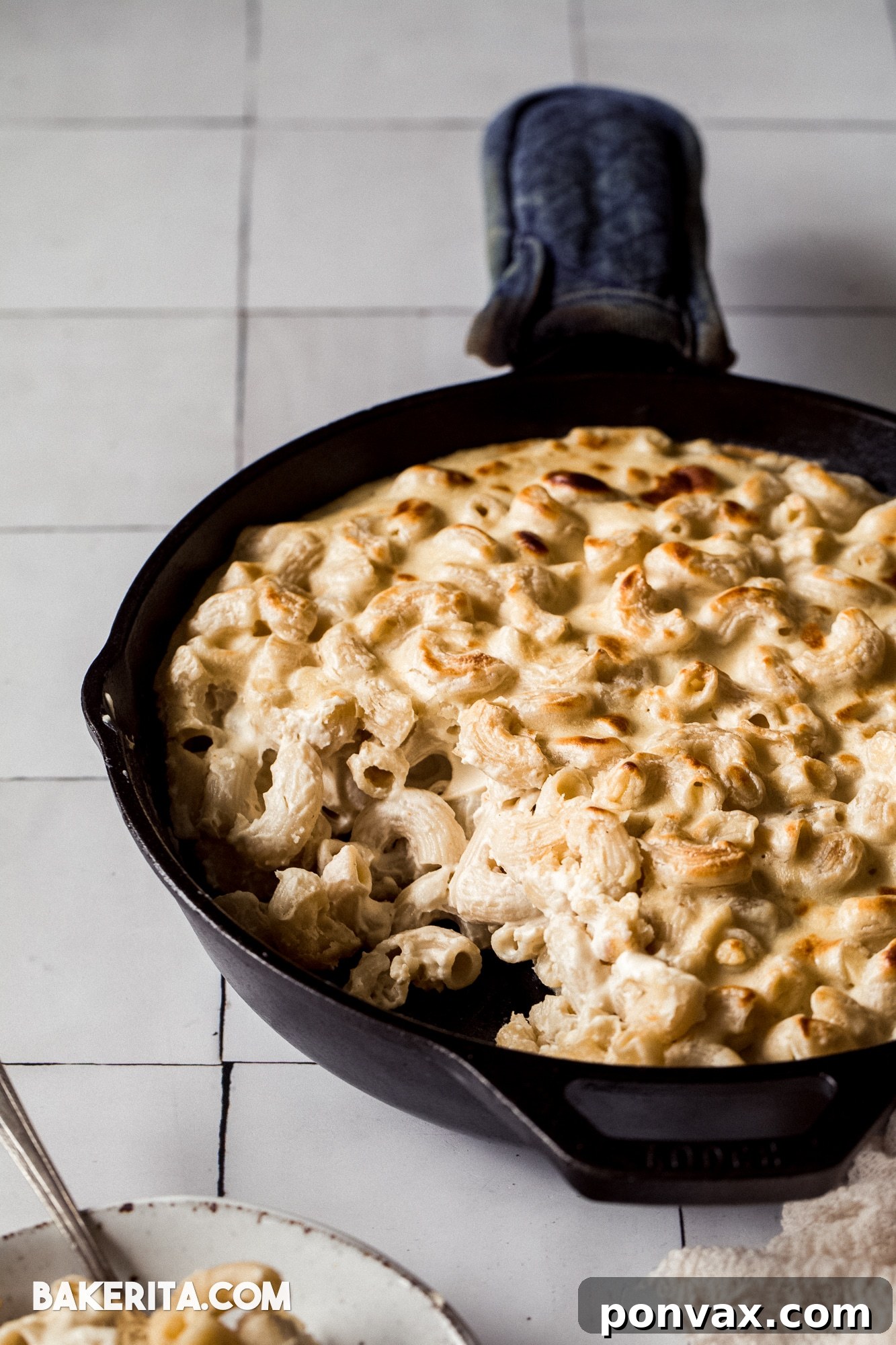 A generous serving of vegan mac and cheese, baked to a golden crisp, presented in a rustic cast-iron pan, ready to be enjoyed.