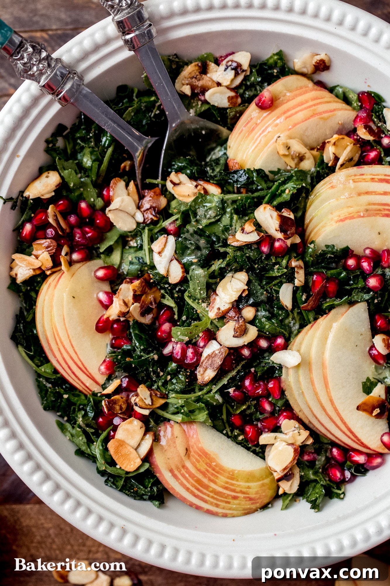 Close-up shot of the Autumn Kale Harvest Salad showcasing the beautiful texture of massaged kale, the vibrant colors of pomegranate and apple, and the sweet glaze on the candied almonds.