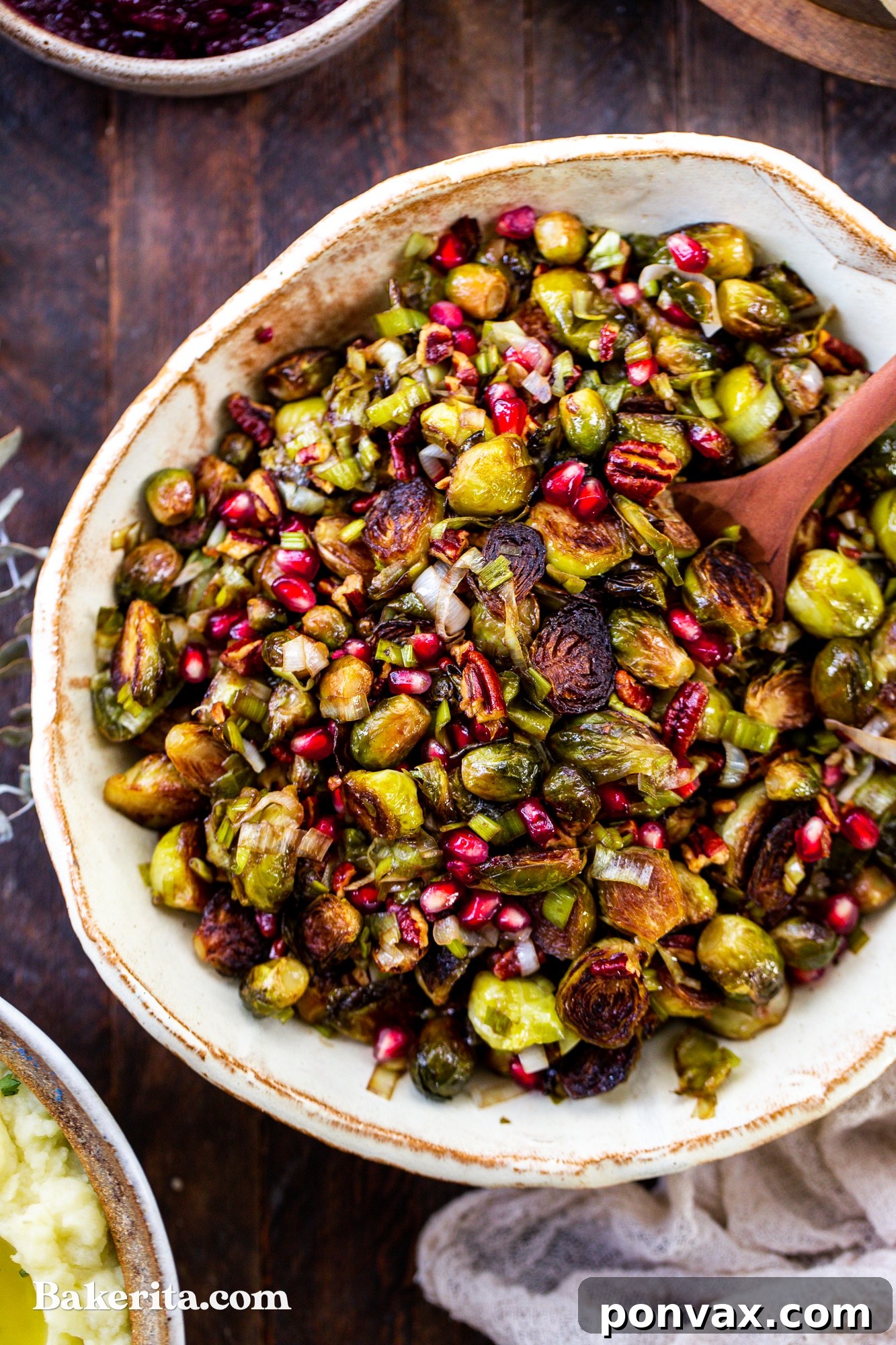 Jewel-Toned Roasted Brussels Sprouts with Pomegranate and Pecans 3 Close-up shot of roasted Brussels sprouts, showing their golden-brown edges and tender centers, mixed with red pomegranate seeds.