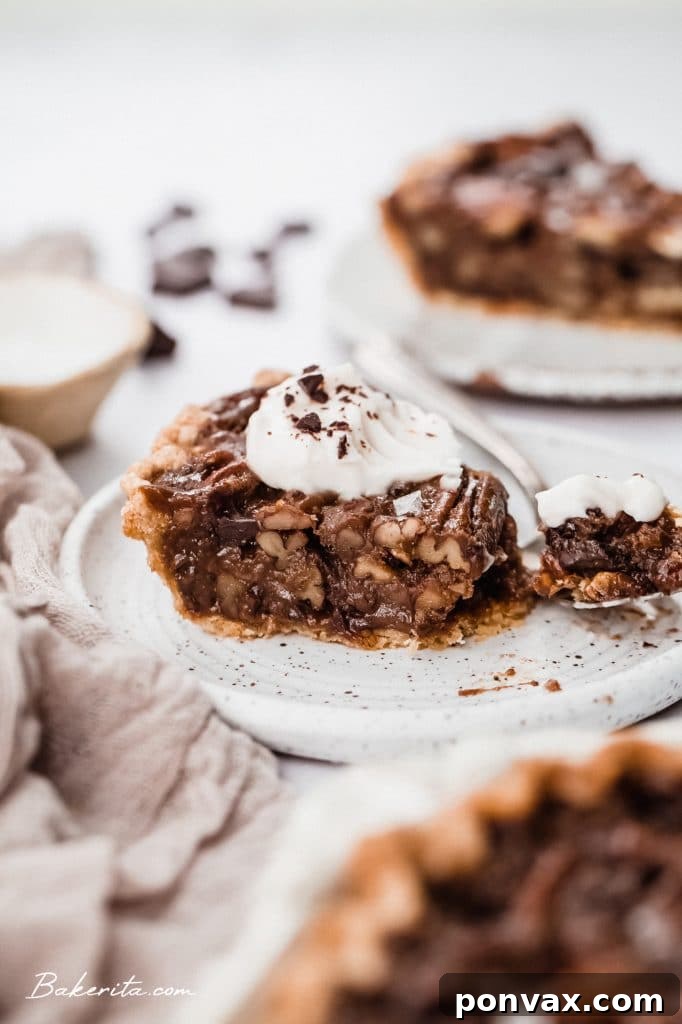 A slice of Vegan Chocolate Pecan Pie with a golden crust and gooey chocolate-pecan filling.