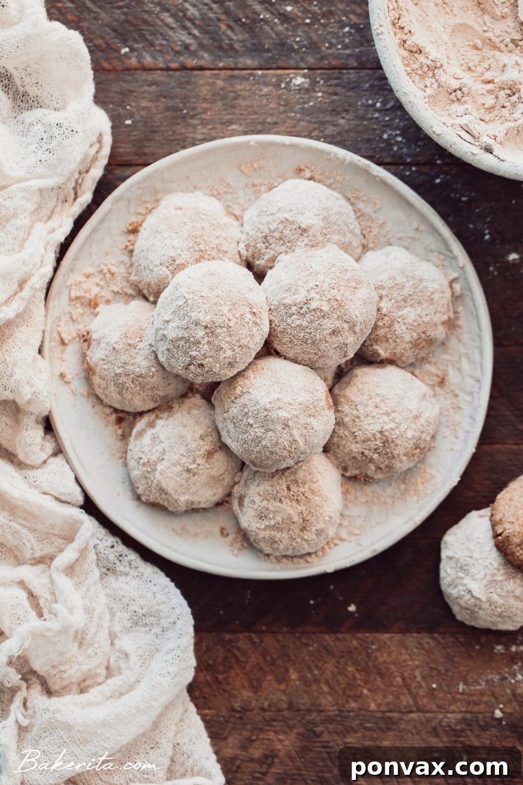 Gluten-Free Vegan Snowball Cookies dusted with powdered sugar, arranged on a rustic wooden surface