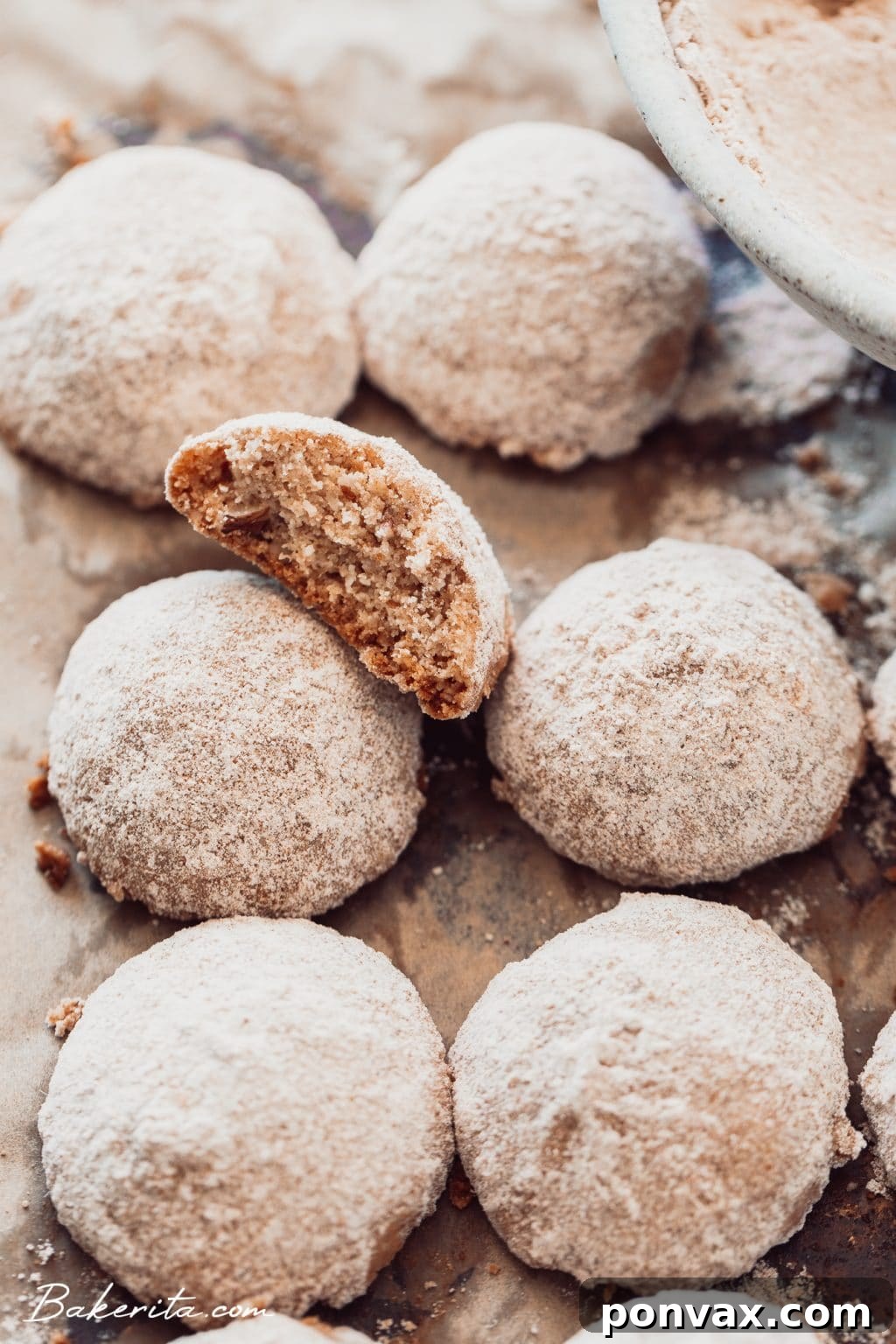 Close-up of a stack of snowball cookies on a white plate, showcasing their snowy coating and crumbly texture