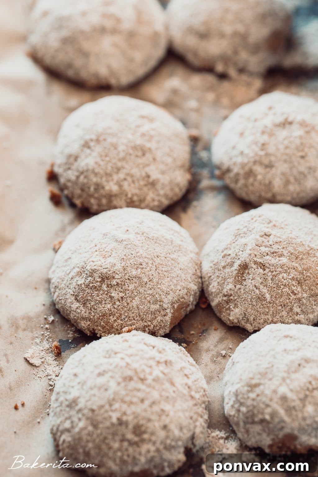 A festive display of snowball cookies on a wooden serving board with holiday decorations