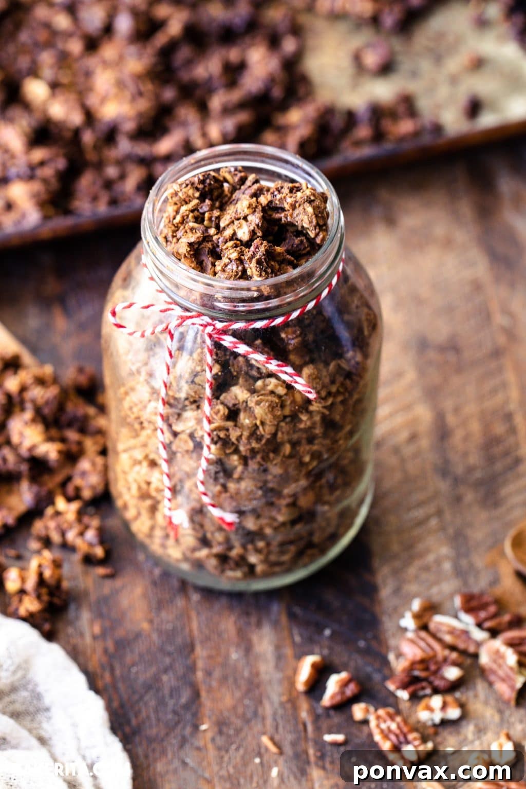 A close-up of a hand reaching for a bowl of freshly baked vegan gingerbread cookie granola, highlighting its appealing texture.