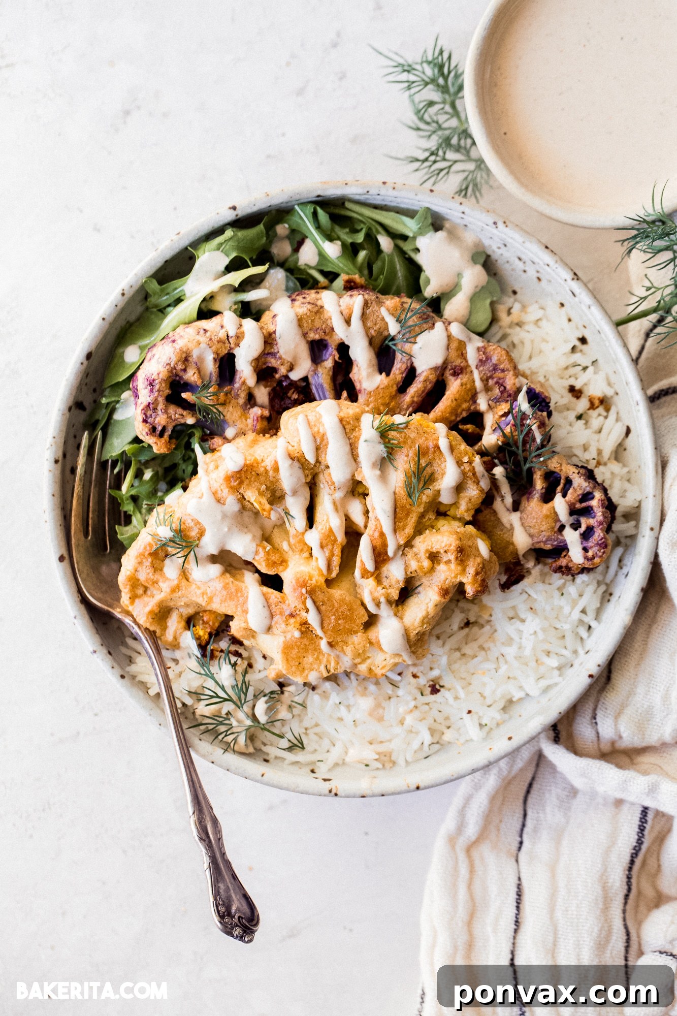 Crispy Vegan Tahini Cauliflower Steaks served on a platter, garnished with fresh herbs.