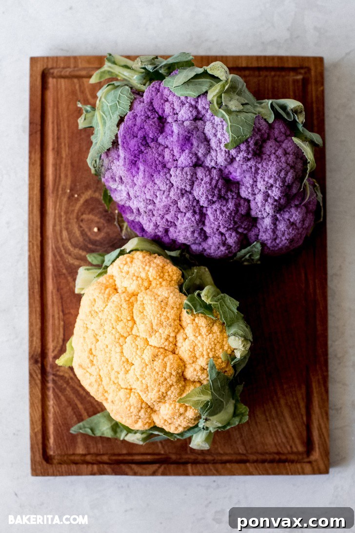 Multiple Vegan Tahini Cauliflower Steaks being prepared on a baking sheet, coated in tahini sauce.