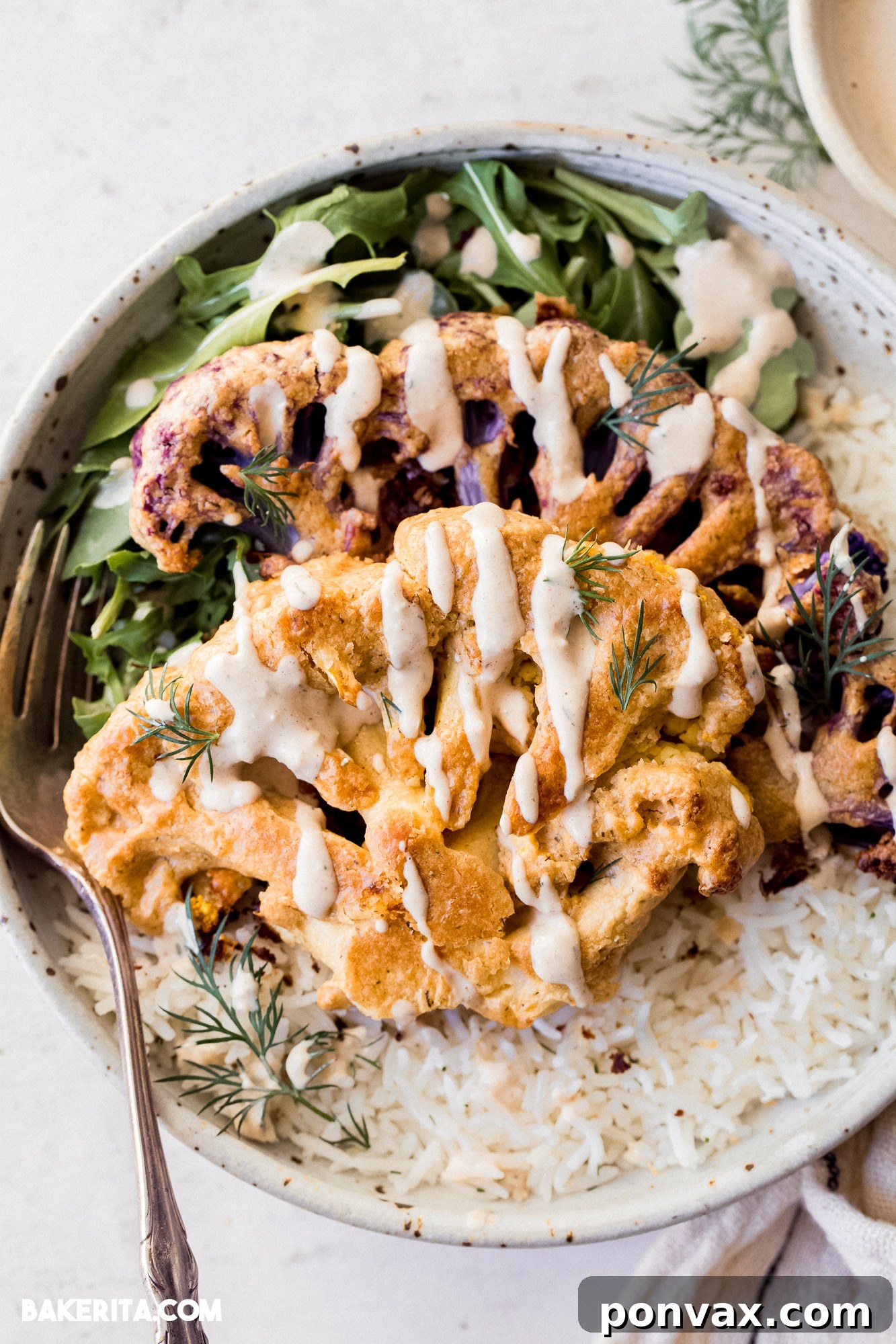 Oven-roasted Vegan Tahini Cauliflower Steaks on a baking sheet, fresh out of the oven, golden and crispy.